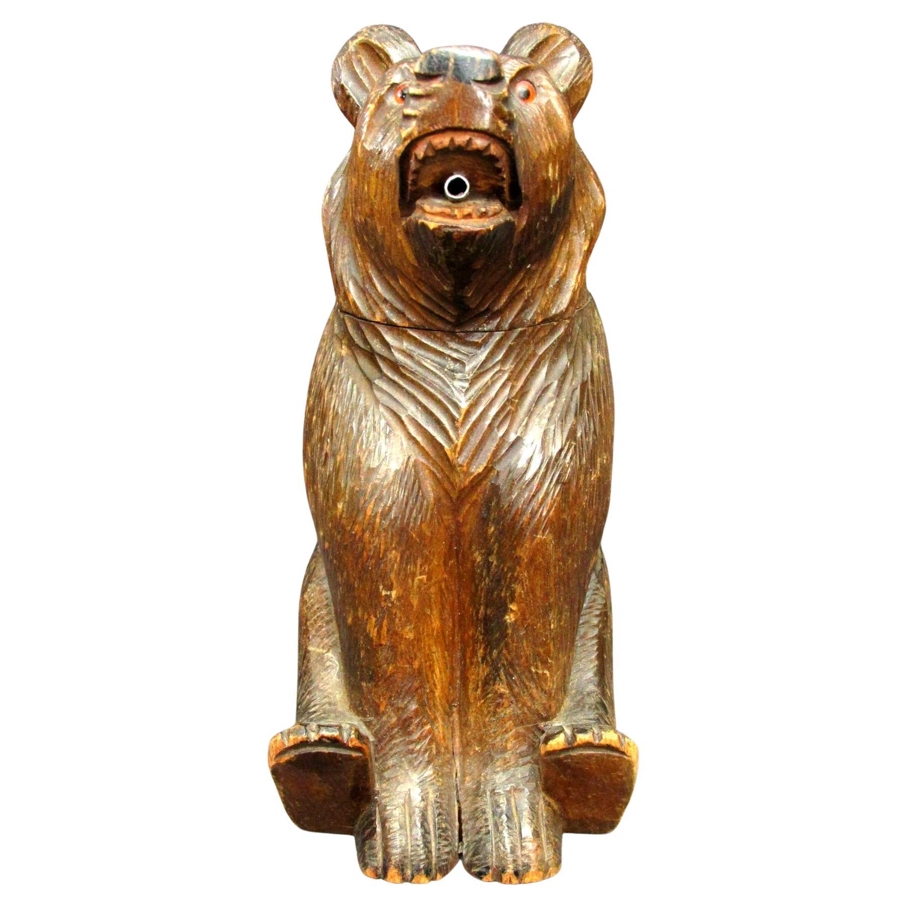 A rare & amusing hand carved Lindenwood figure of a seated bear encasing its original glass liner, fitted with a removable head with amber colored glass eyes, the mouth fitted with a pour spout.