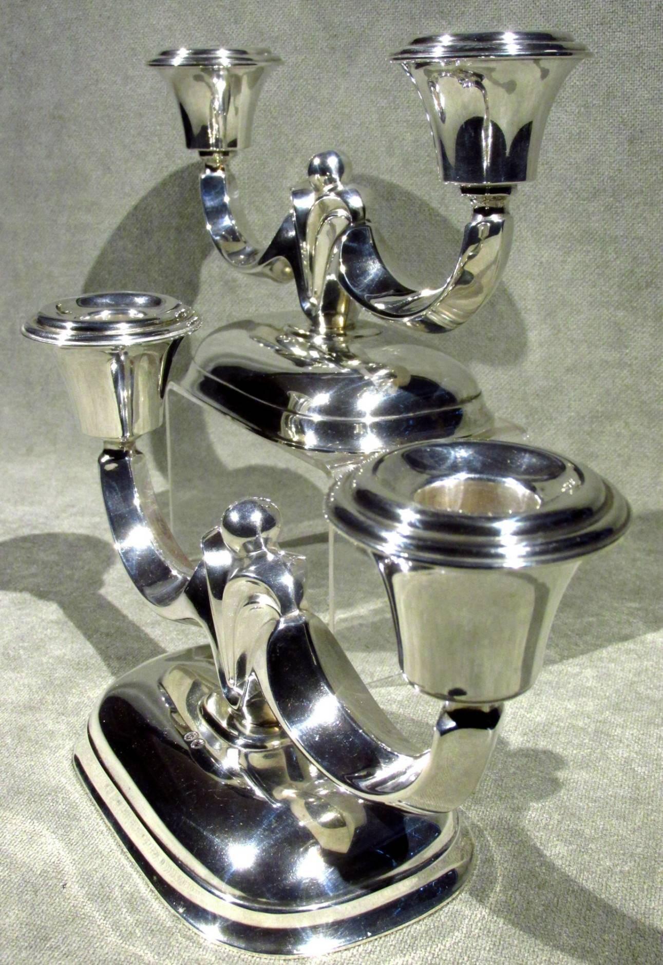 A very good pair of Mid-Century modernist Danish silver (.830 fine) twin branch candelabra, each showing twin cavetto-shaped branches radiating from an anthemia-inspired column, raised upon a domed rectangular weighted base.
(International clients