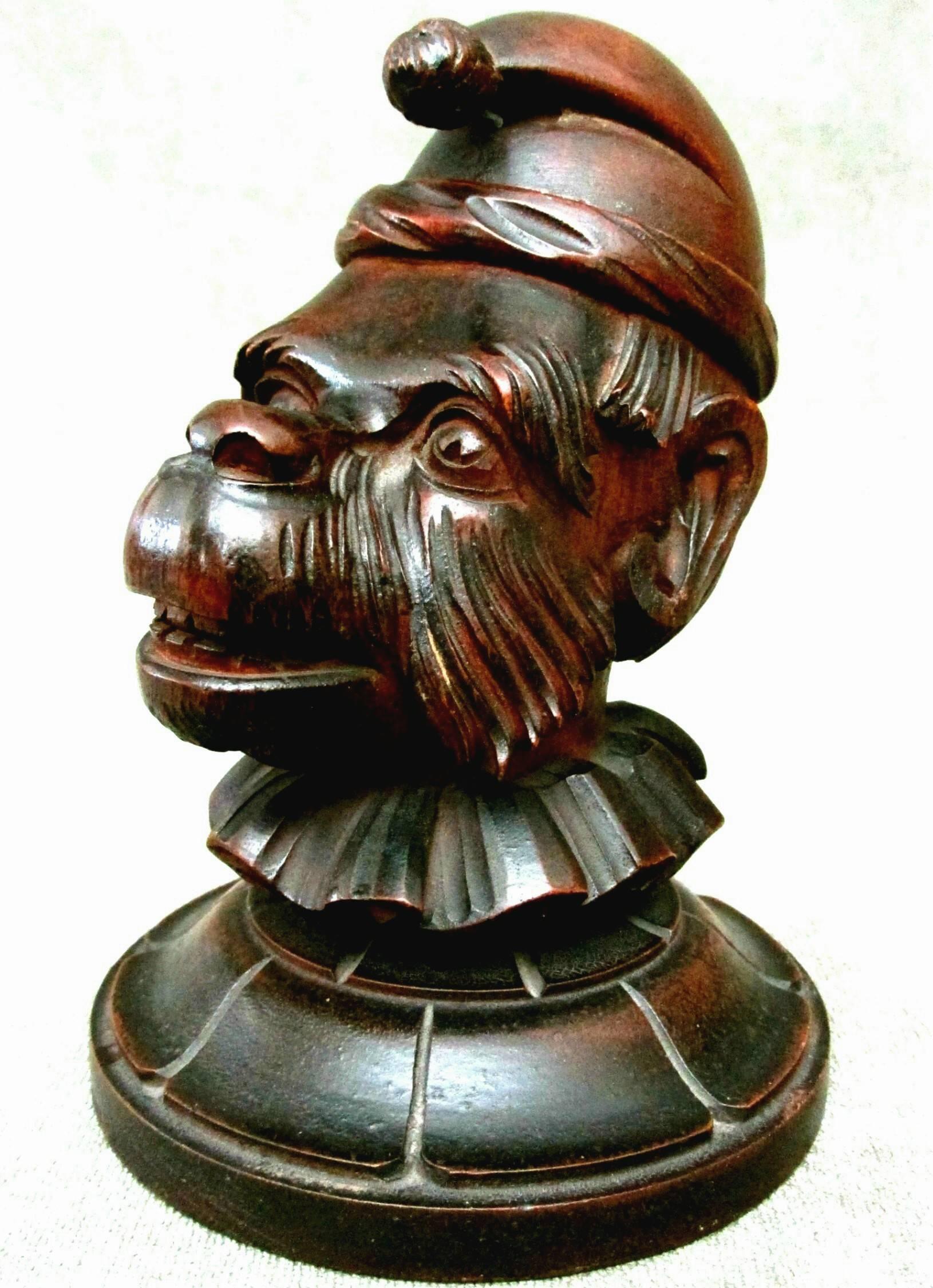 A very unusual if not unique tobacco humidor, showing a realistically carved monkey wearing a cap and a ruffled collar, the face rendered with an amusing expressive grin, the hinged cap opening to a recessed interior. Both ears are pierced