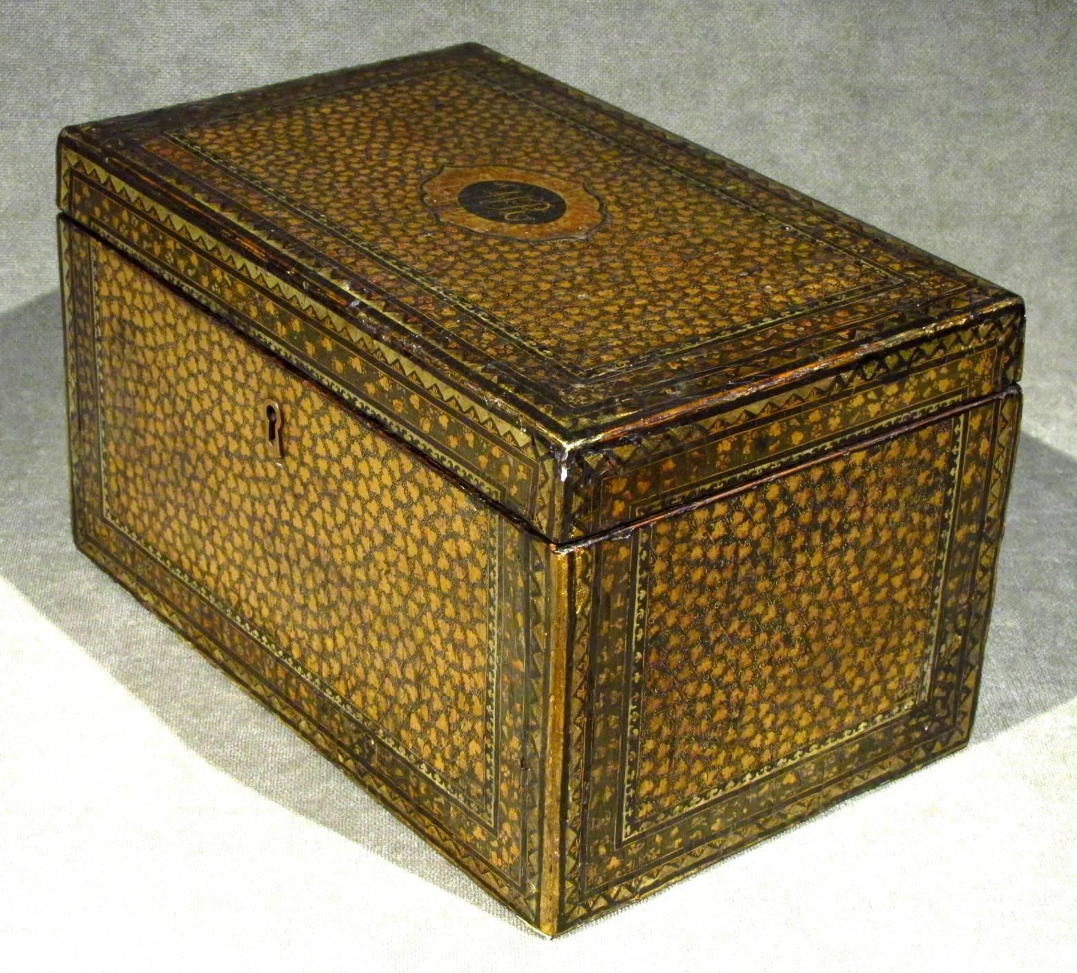 The exterior decorated overall in black lacquer with hand-painted gilt foliate motifs, the hinged lid opening to reveal three oblong pewter canisters, the central canister used for blending, flanked on either side by matching canisters intended for