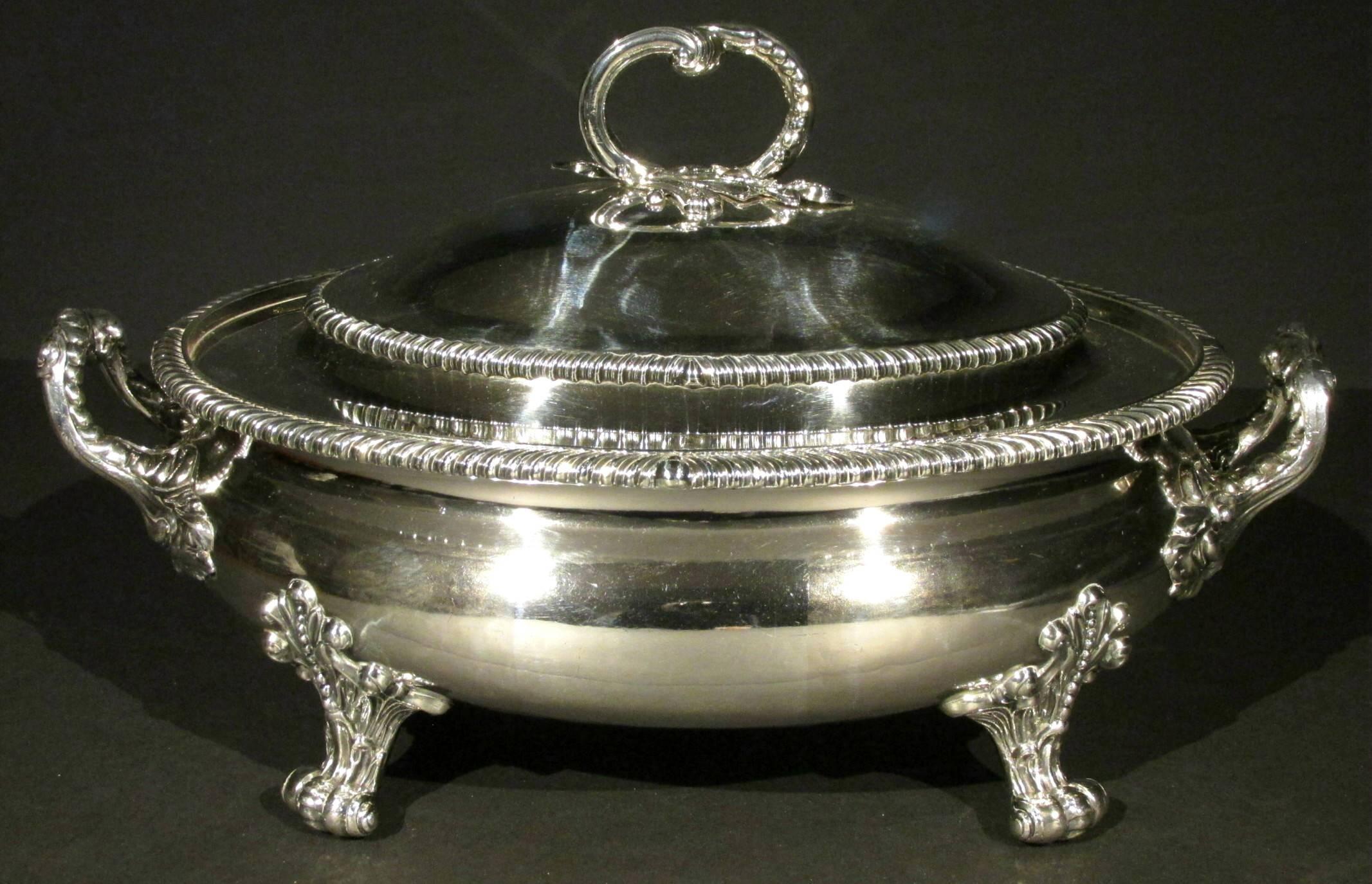 The oval bellied body rising to a gadroon decorated rim and applied foliate cast handles, one side bearing a large ‘let-in’ sterling silver lozenge engraved with a heraldic crest, coat-of-arms and motto 'UBI AMOR IBI FIDES' (Where there is Love