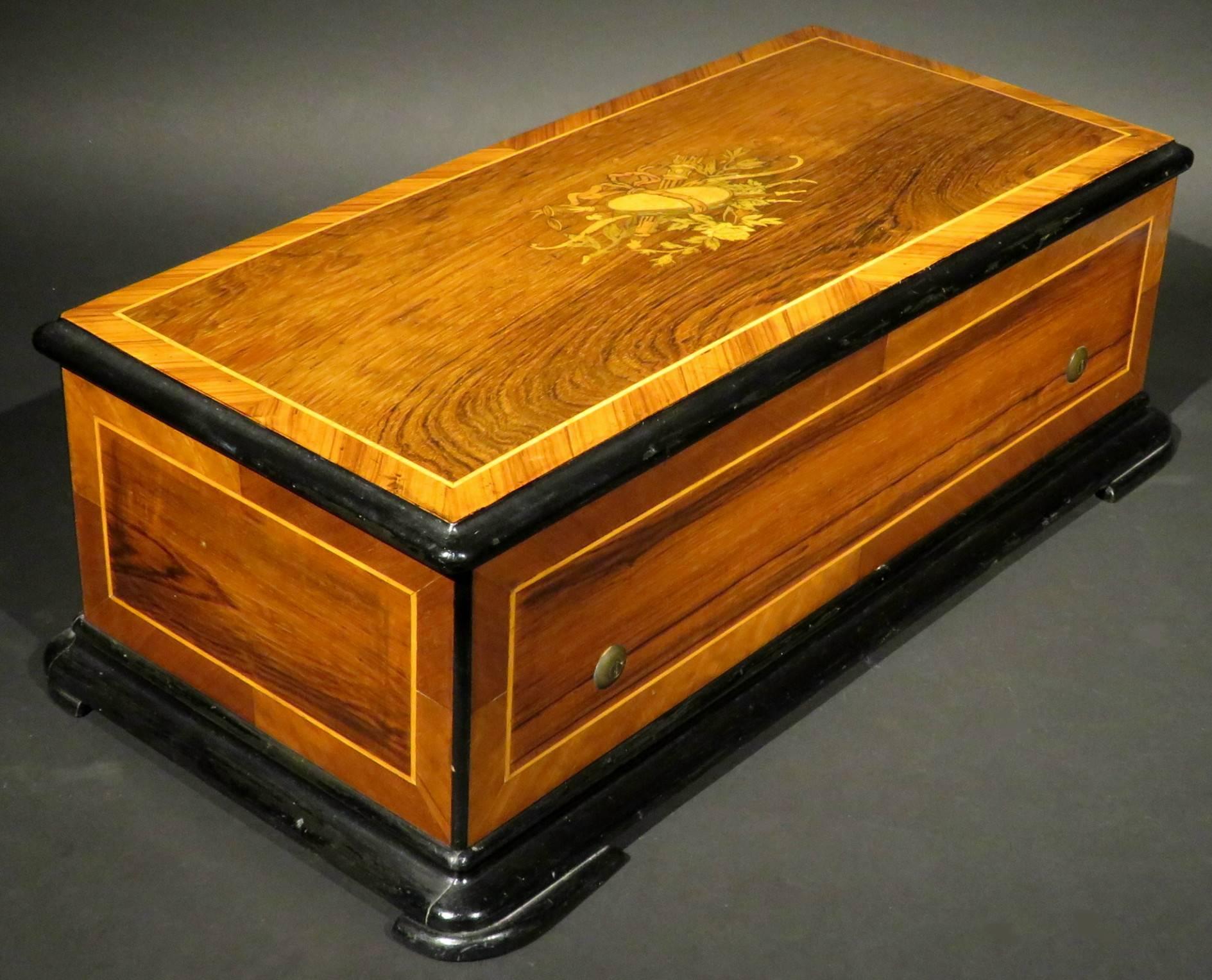 The richly figured rosewood case showing kingwood cross-banded and satinwood strung detail, the top inlaid with marquetry of classical motifs in exotic woods, opening to an ebonized interior with a hinged kingwood framed glass dust-cover over a