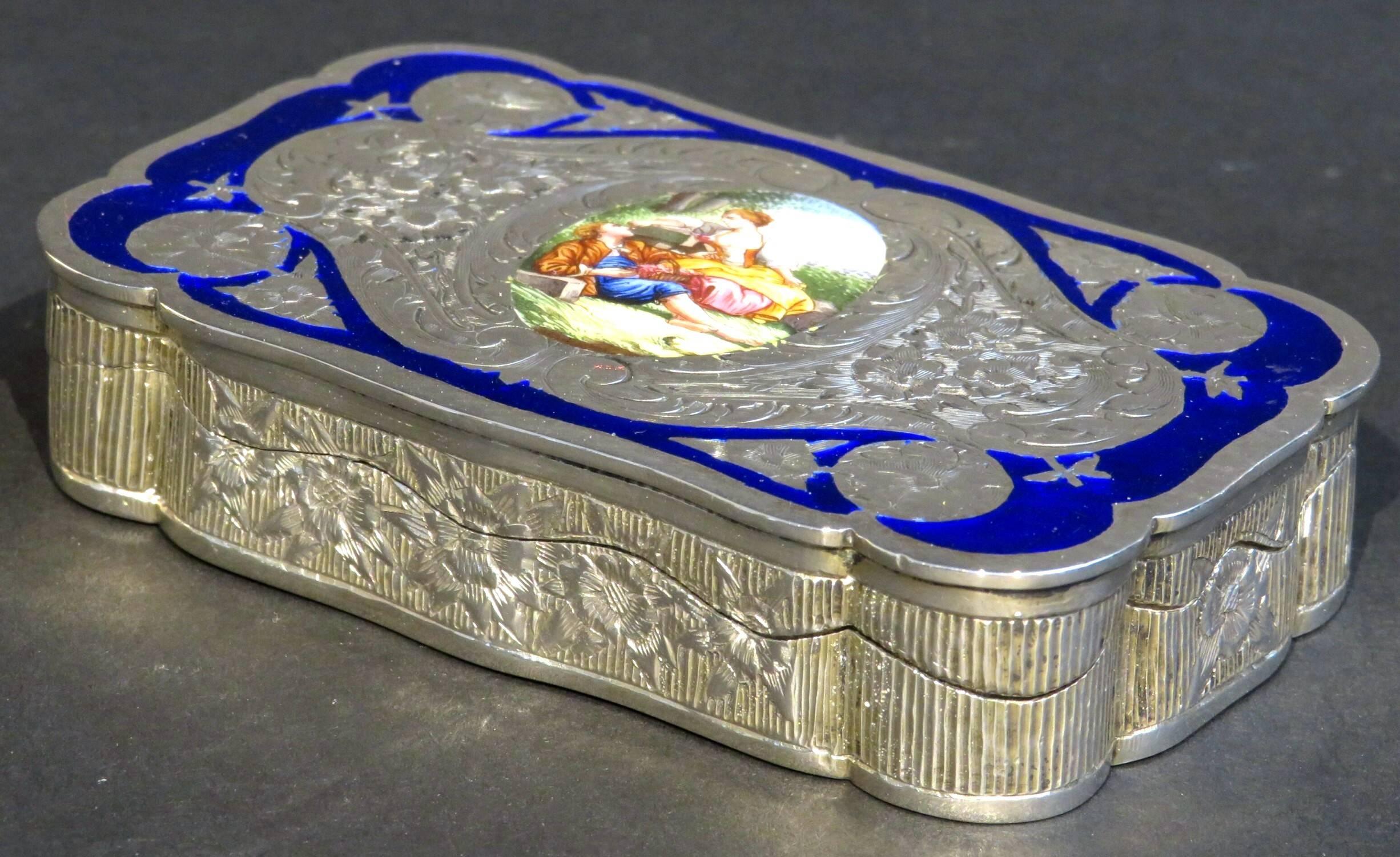 The foliate chased body having a hinged top decorated with a hand-painted romantic vignette in enamels within a cobalt enamel cartouche opening to a gilt washed in interior, the sides decorated with foliate chased detail against a reeded field. The
