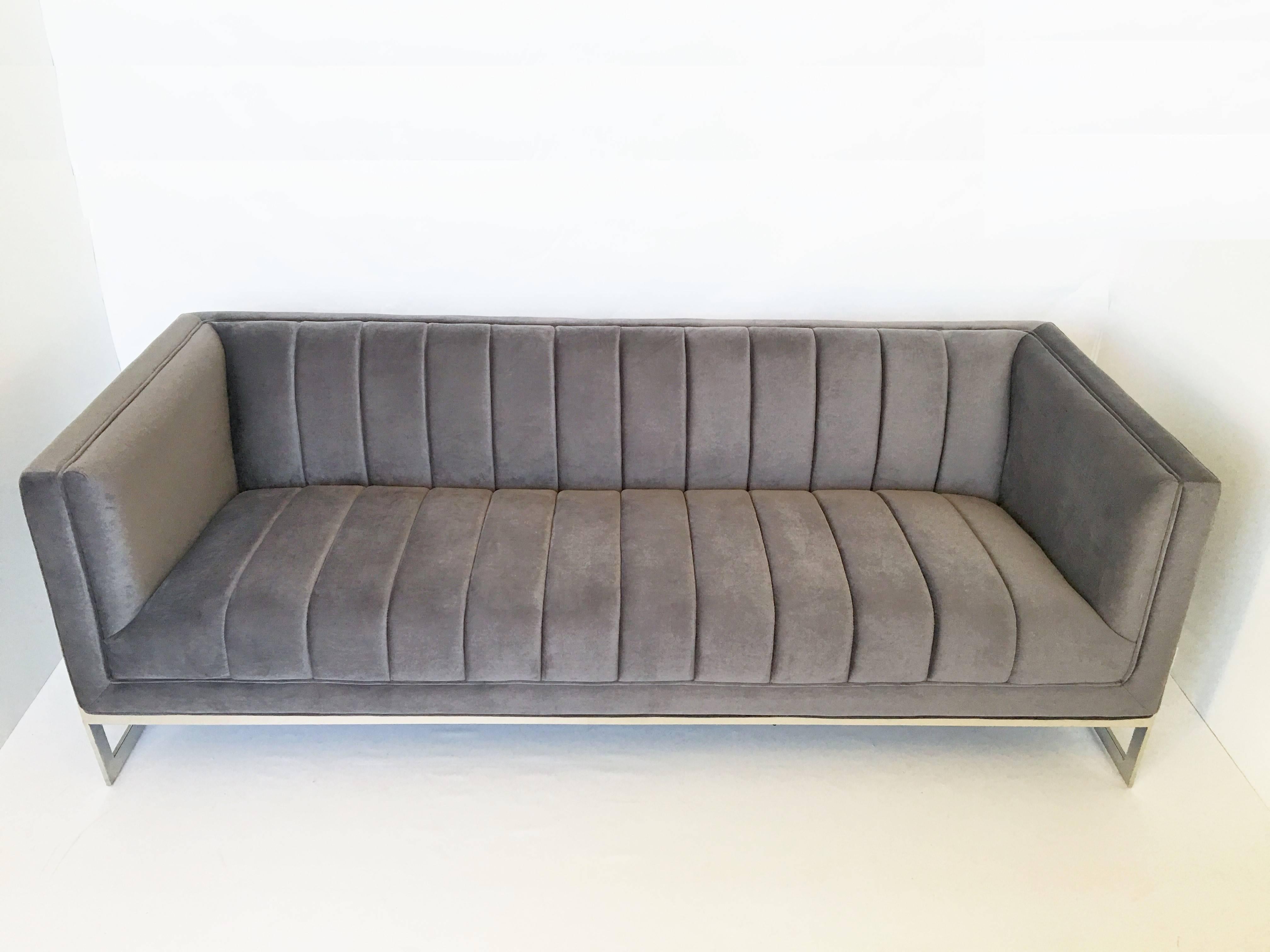 This stunning sofa features a very sleek sophisticated design with channeled seat and back detailing with a chrome frame sofa. Offering a contemporary flair with a touch of sophistication, newly upholstered in velvet this sofa is unique yet