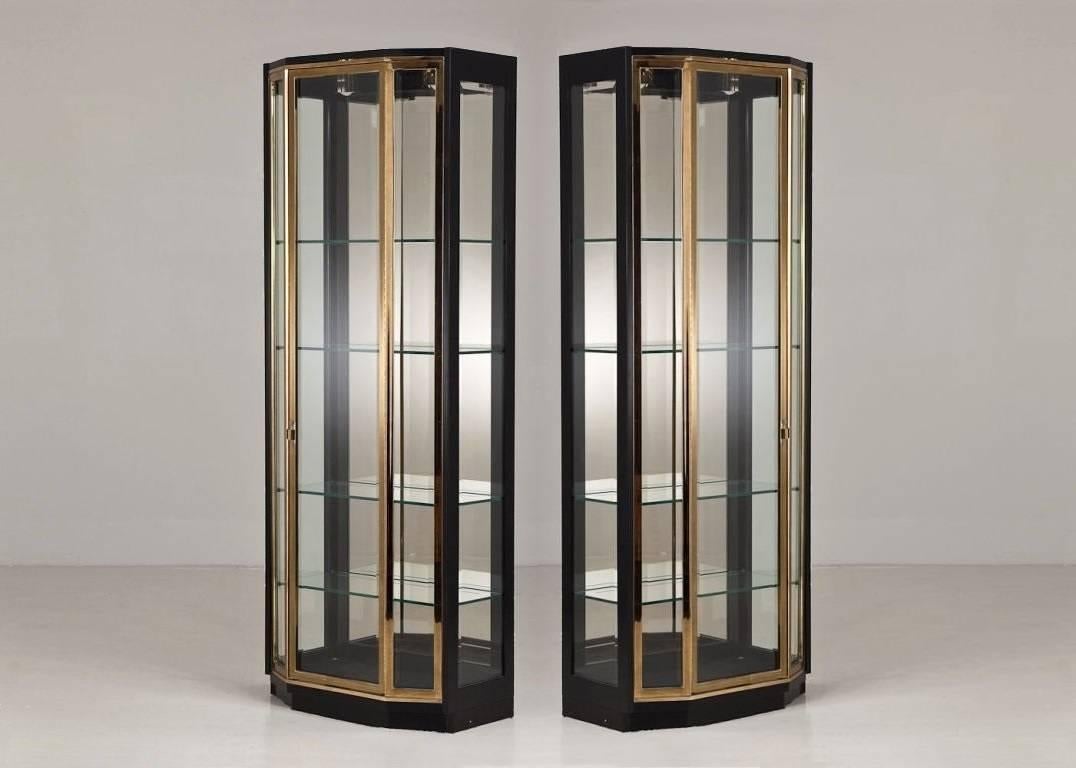 Exceptional pair of tall 1970s black lacquer and brass vitrine by Henredon. Featuring clean lacquered frames with brass trim on the doors. The cabinets feature beveled glass sides and doors that open to reveal four adjustable glass shelves, mirrored