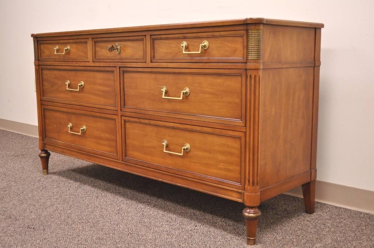 A lovely and very charming directoire chest in the Louis XVI taste by Kindel Furniture. The piece features reeded column-form corners, flanked by fluted bronze mounts, seven dovetailed drawers, brass hardware, raised on tapering bulbous legs ending