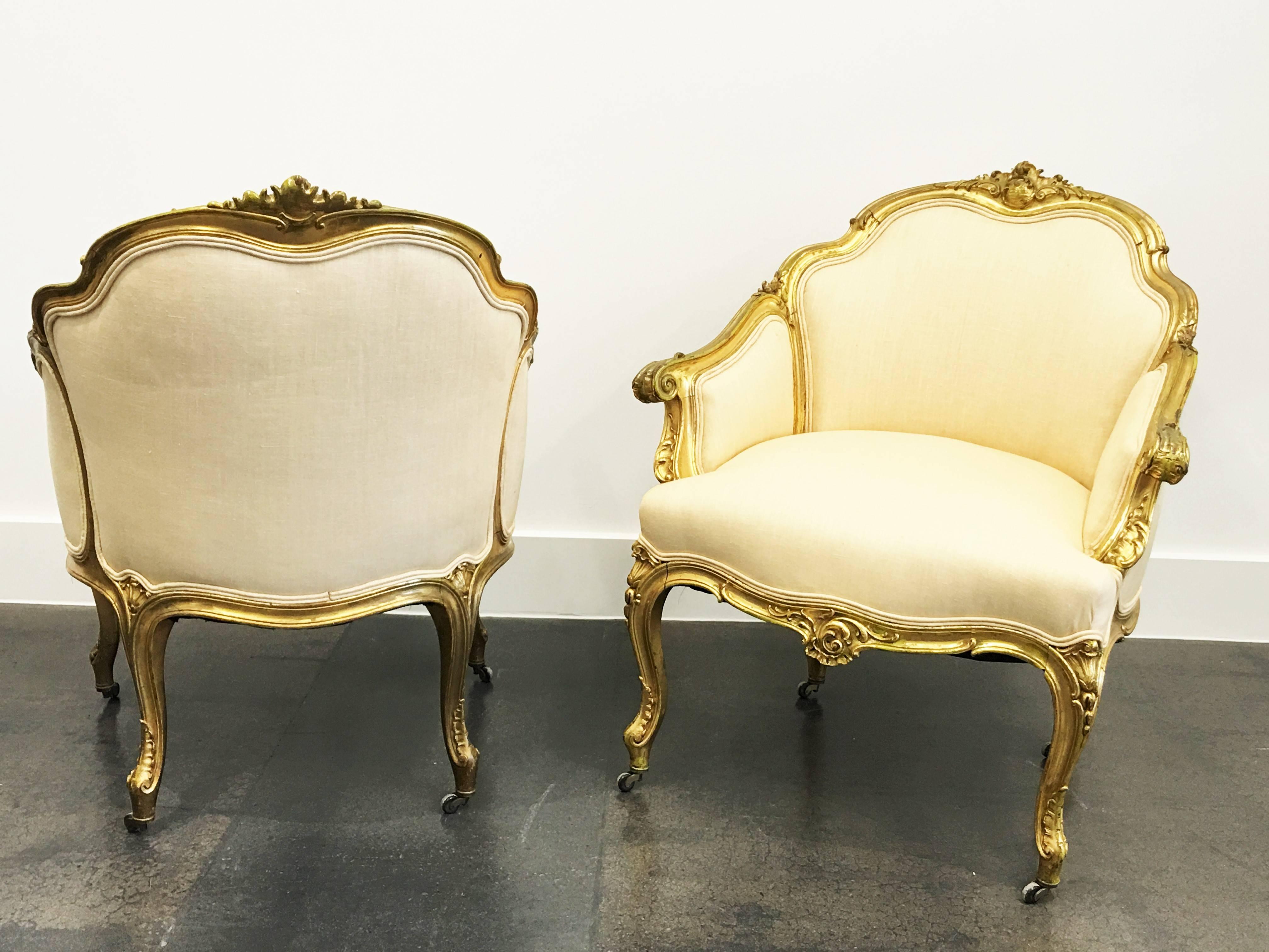 A wonderful pair of 19th century Louis XV giltwood bergeres. Features a carved giltwood frame. Raised by elegant cabriole legs with charming foliate carvings, centered by a fine pierced fluted seashell cabochon at the arbalest shaped frieze. The