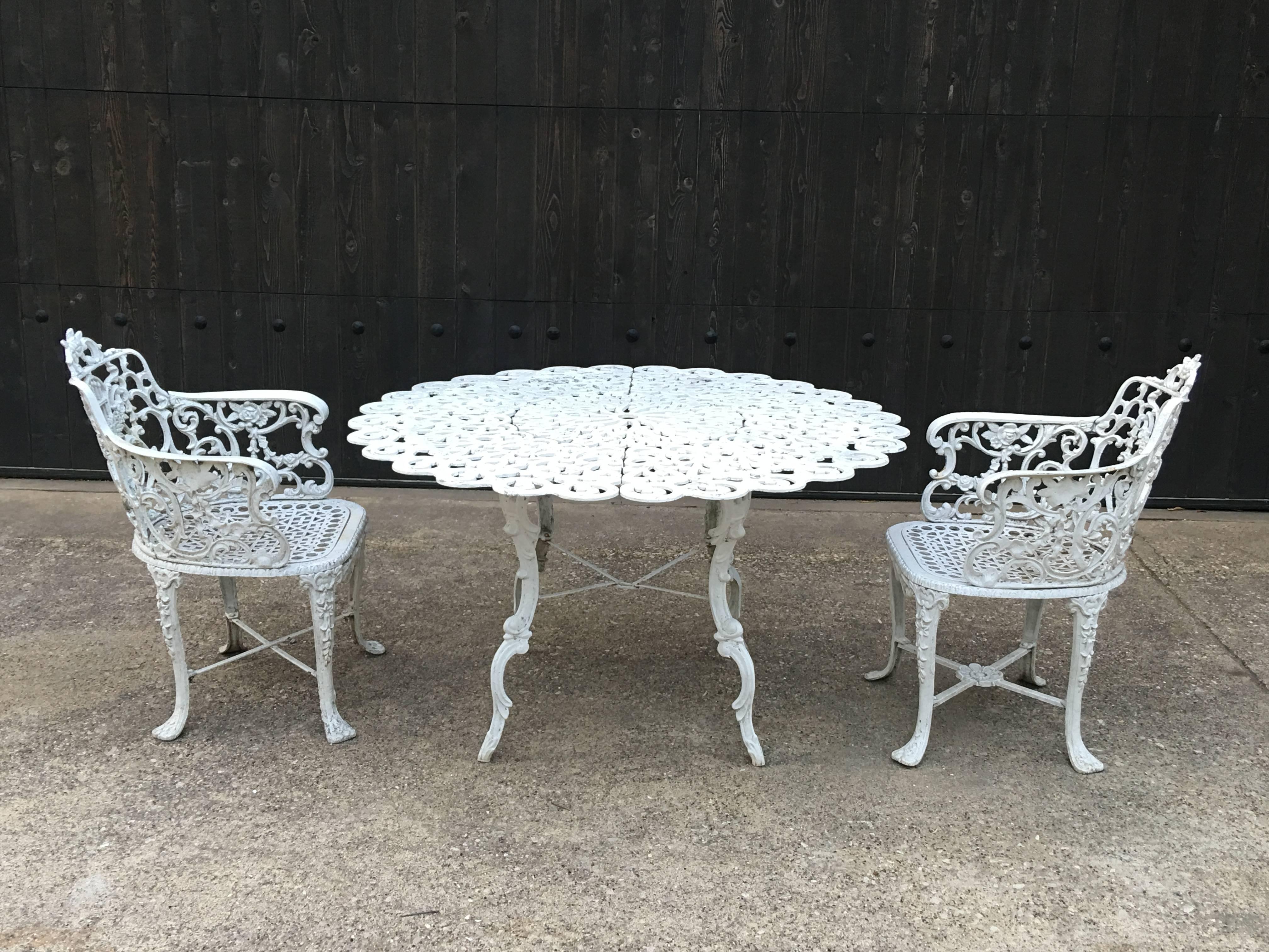 Robert wood foundry, circa 1853 heavy cast iron white painted garden set, which includes six armchairs and a round table. All cast with open foliate c -scrolling backs with lyre-style motif, cabriole legs cast with bell flowers. Each chair is