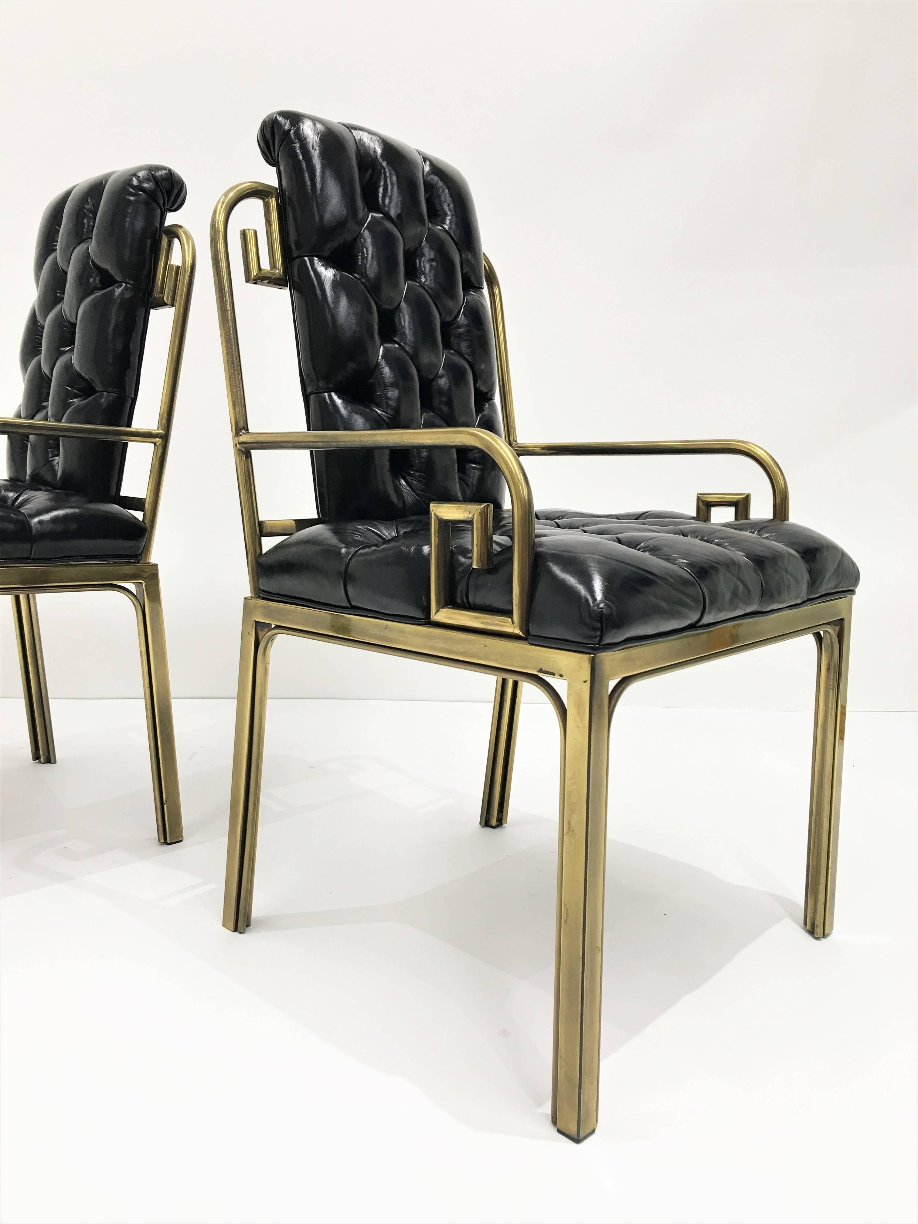 Stunning pair of 1960s Mastercraft dining chairs with Greek key details. They retain their original black leather upholstery. The brass retains its original warm patina.