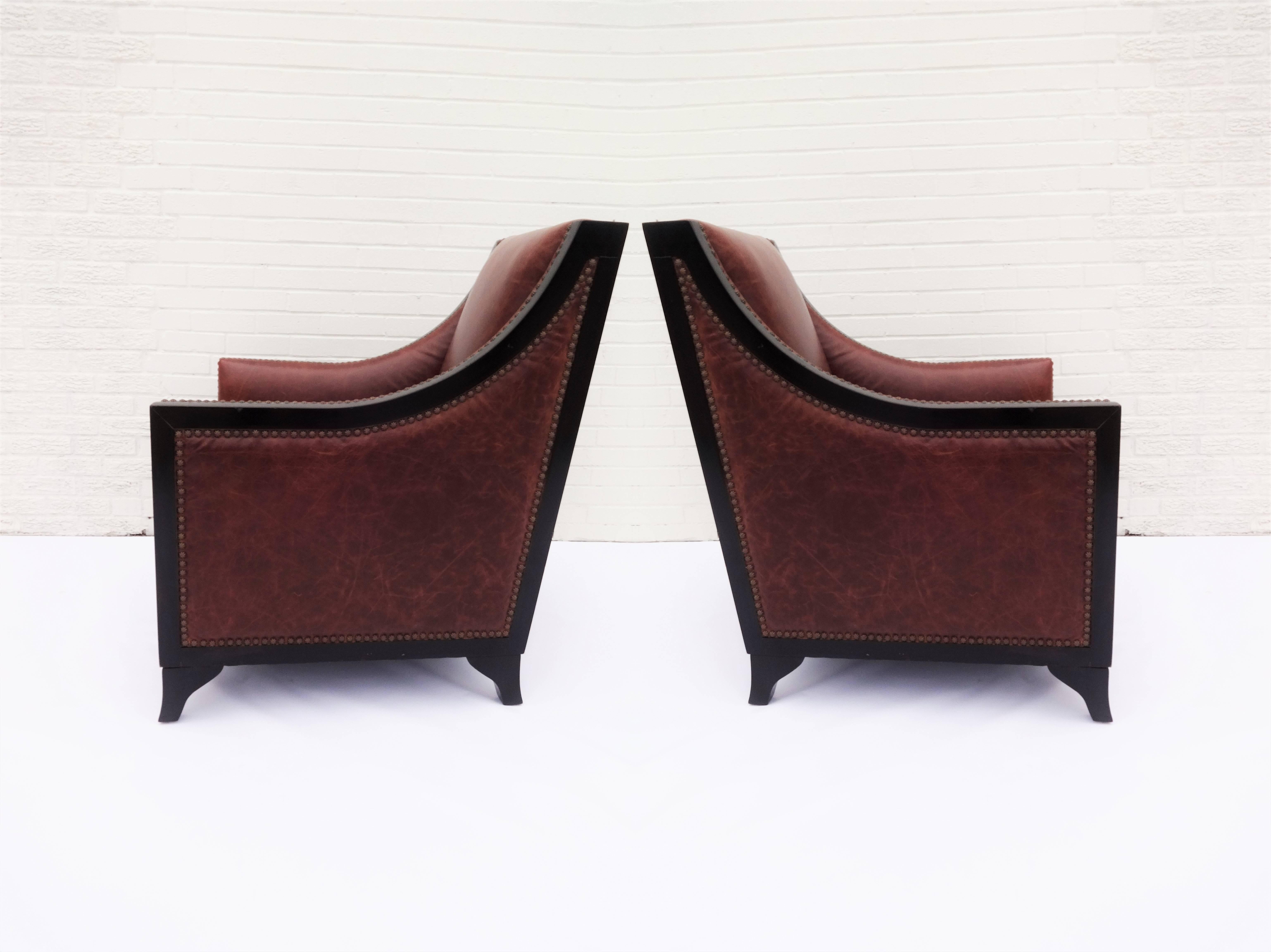 Pair of French Art Deco club chairs in rich cognac colored leather. Nice patina, all the hallmarks of natural leather including scars, stretch marks, grain and texture variations. This chair is finished with studding which is achieved with close