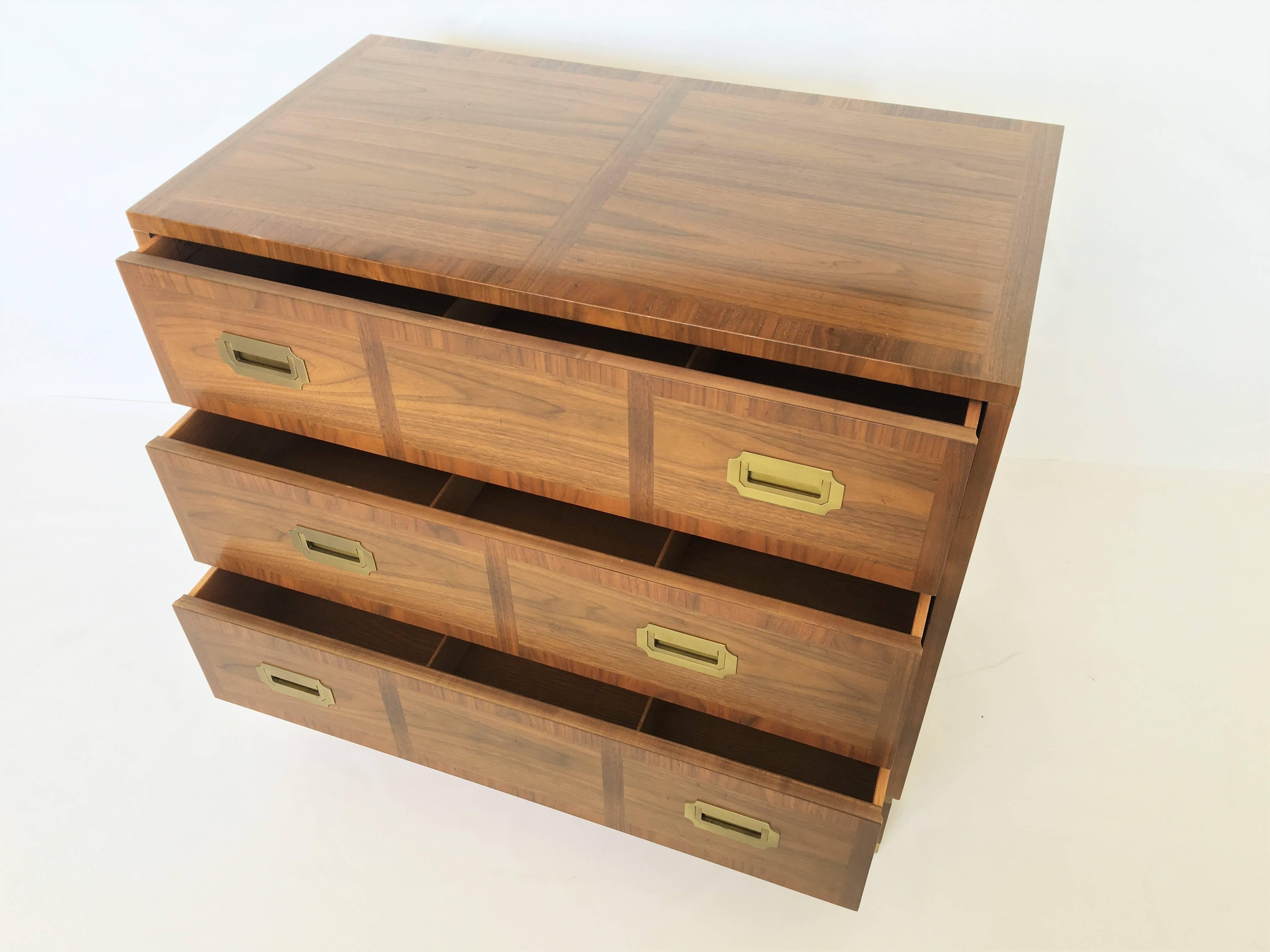 Pair of vintage Mid-Century Modern Campaign style milling road bachelors chests by Baker with Classic simple form. Each chest features a very nice Hollywood Regency/Campaign style design with striking, figured wood grain, three dovetailed banded