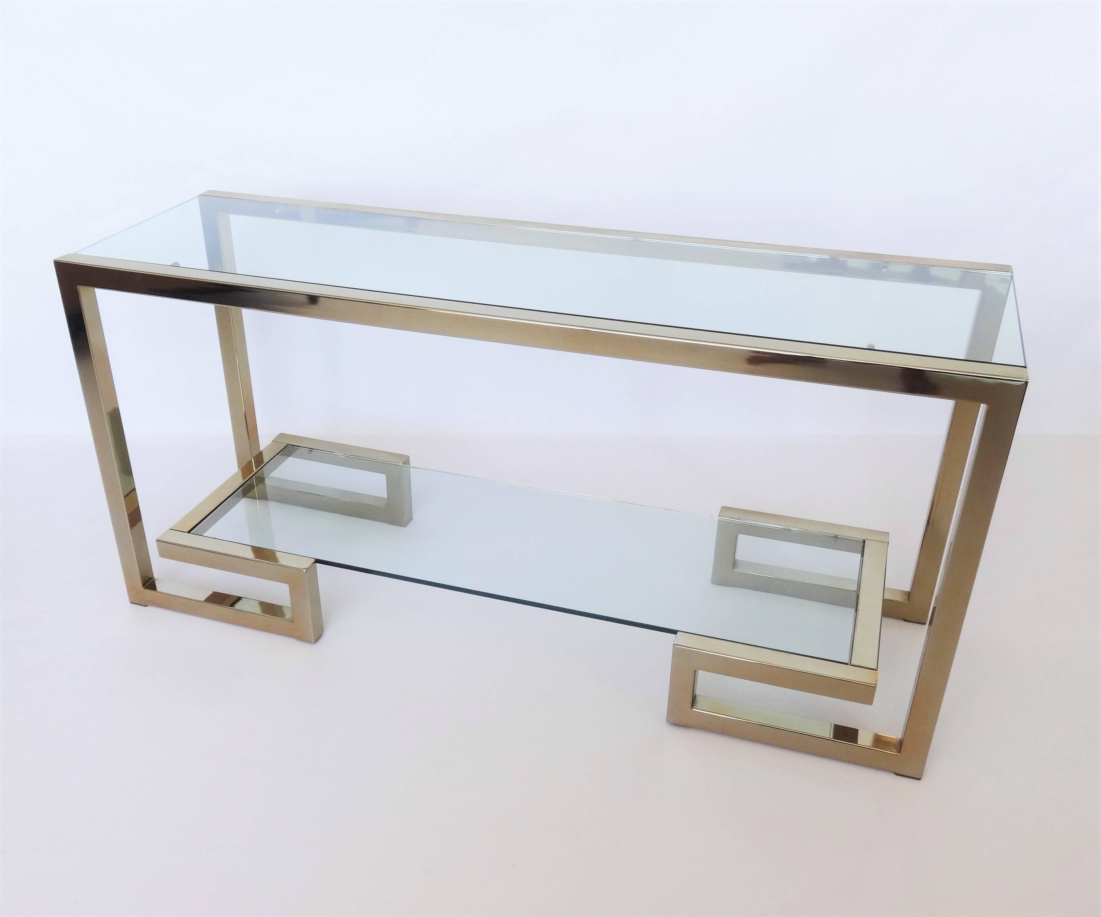 Statement making Milo Baughman style console. Striking from every angle. This console table has two floating shelves, and the bottom shelf sits on a Greek key base. Glass with polished brass frame. Finished on all sides.