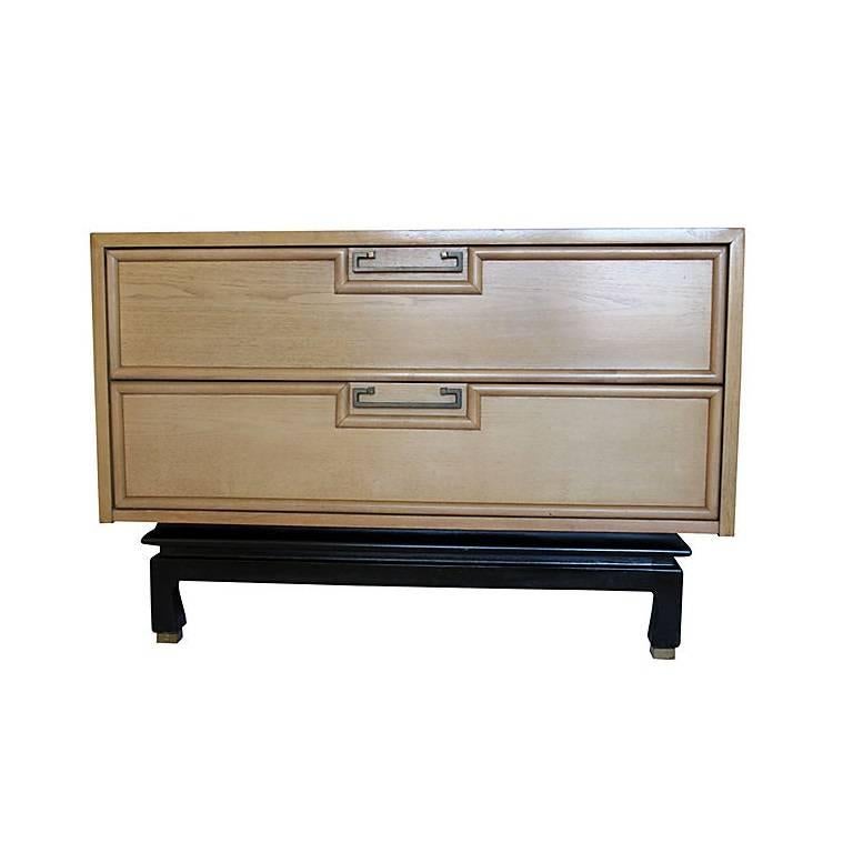 This grand scale sleek bedside table designed with a slight Asian flair. Feature two stacked drawers with beveled trim and dovetail joinery, and an ebonized stepped apron with four short feet with brass capped legs. Hardware includes brass pulls.