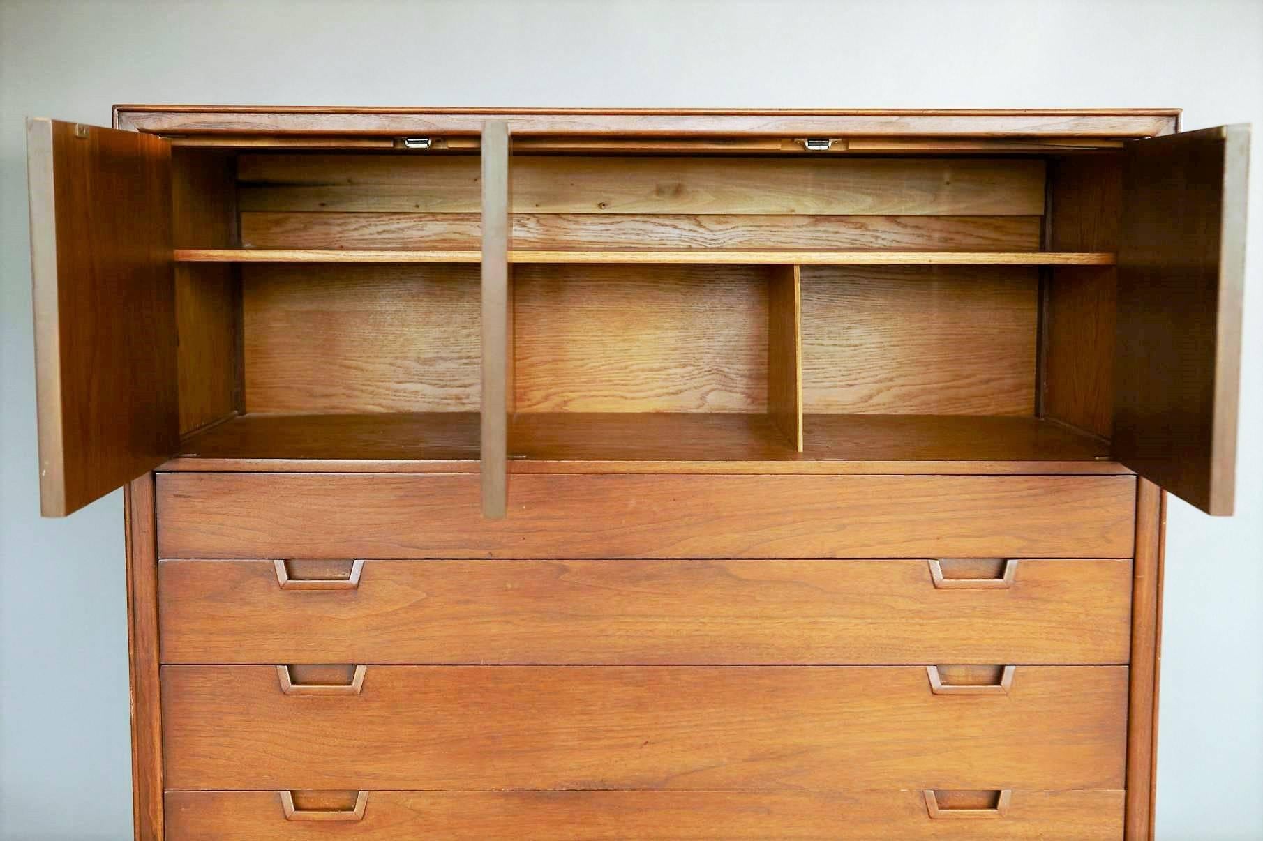 This stylish chest of drawers was designed as part of the Janus Collection by the Mount Airy Furniture Company for John Stuart, N.Y.C. It is made of walnut wood and has patterned inlay on the cabinet doors as well as on the top and sides. Note the