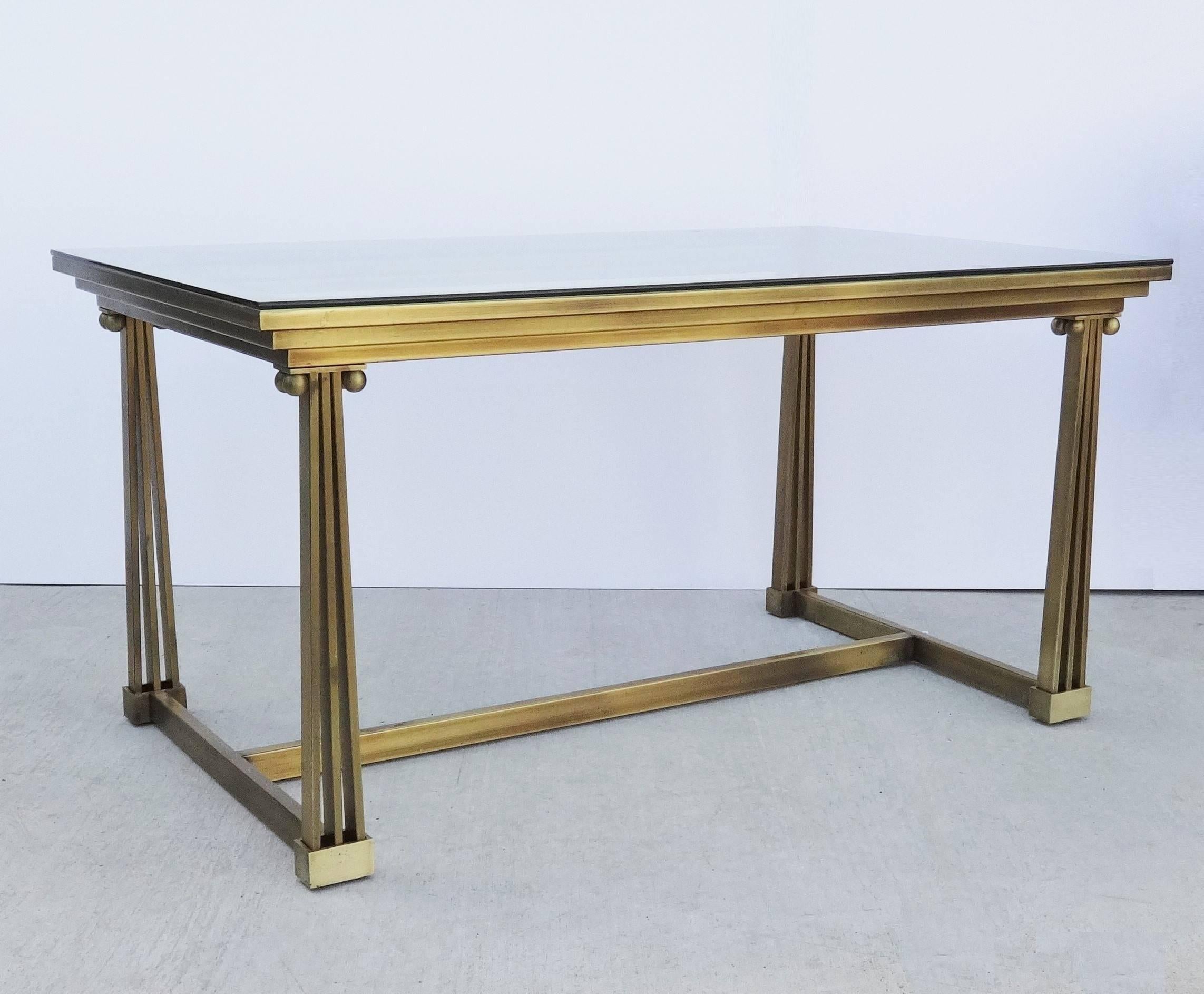 Attributed to Mastercraft (American, 1946-1985), probably 1970s. A polished brass and glass desk, writing table or dining table having a rectangular projecting and stepped top inset with conforming glass supported by  four legs modeled as Ionic
