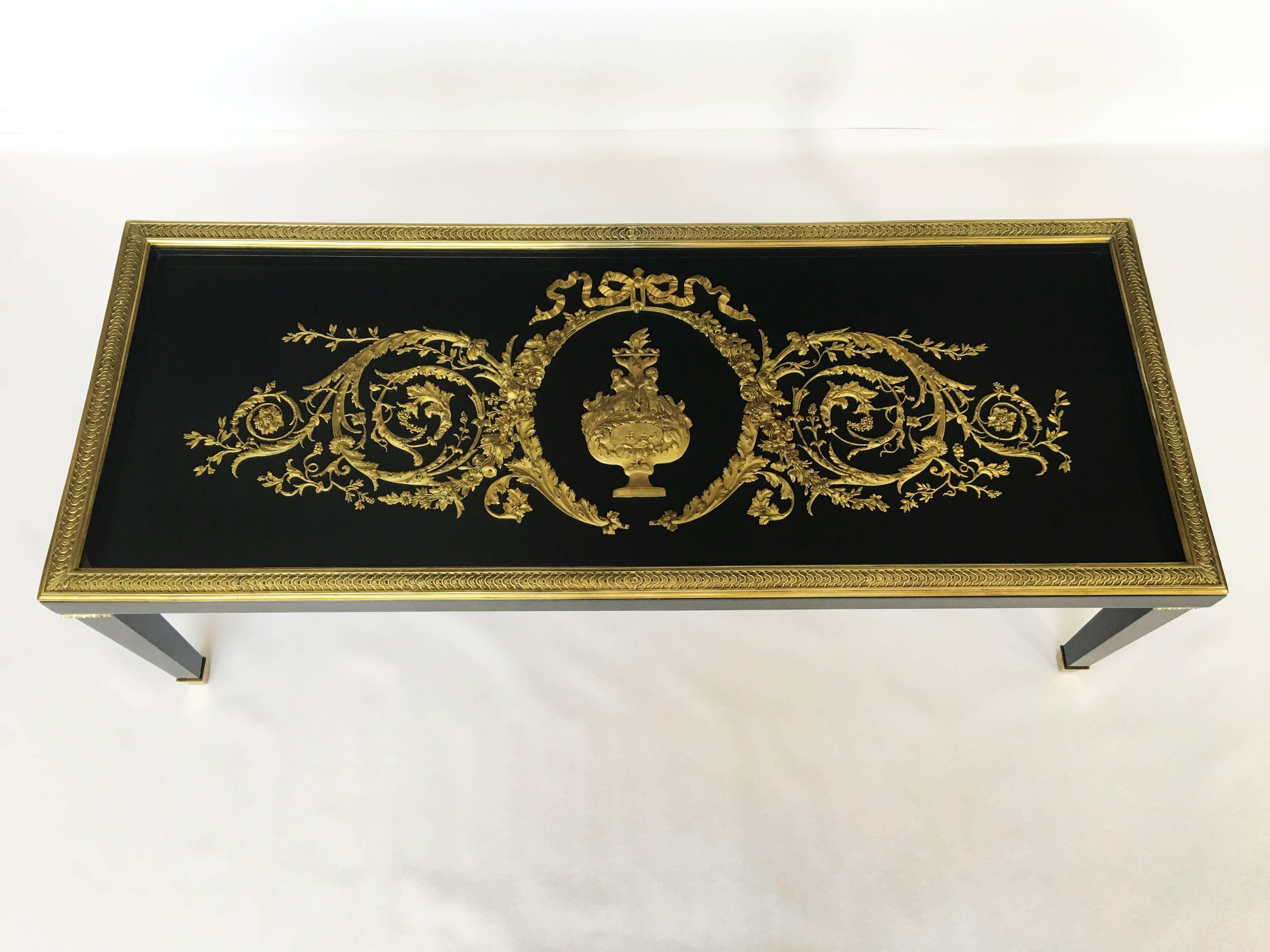 A rare ebonized frame, glass top and gilt brass-mounted centre table attributed to Alfred-Emmanuel Beurdeley. Adorned with finely cast gilt bronze scrolls, with reliefs of female figures surmounted by ribbon ties and flanked by foliage and laurel