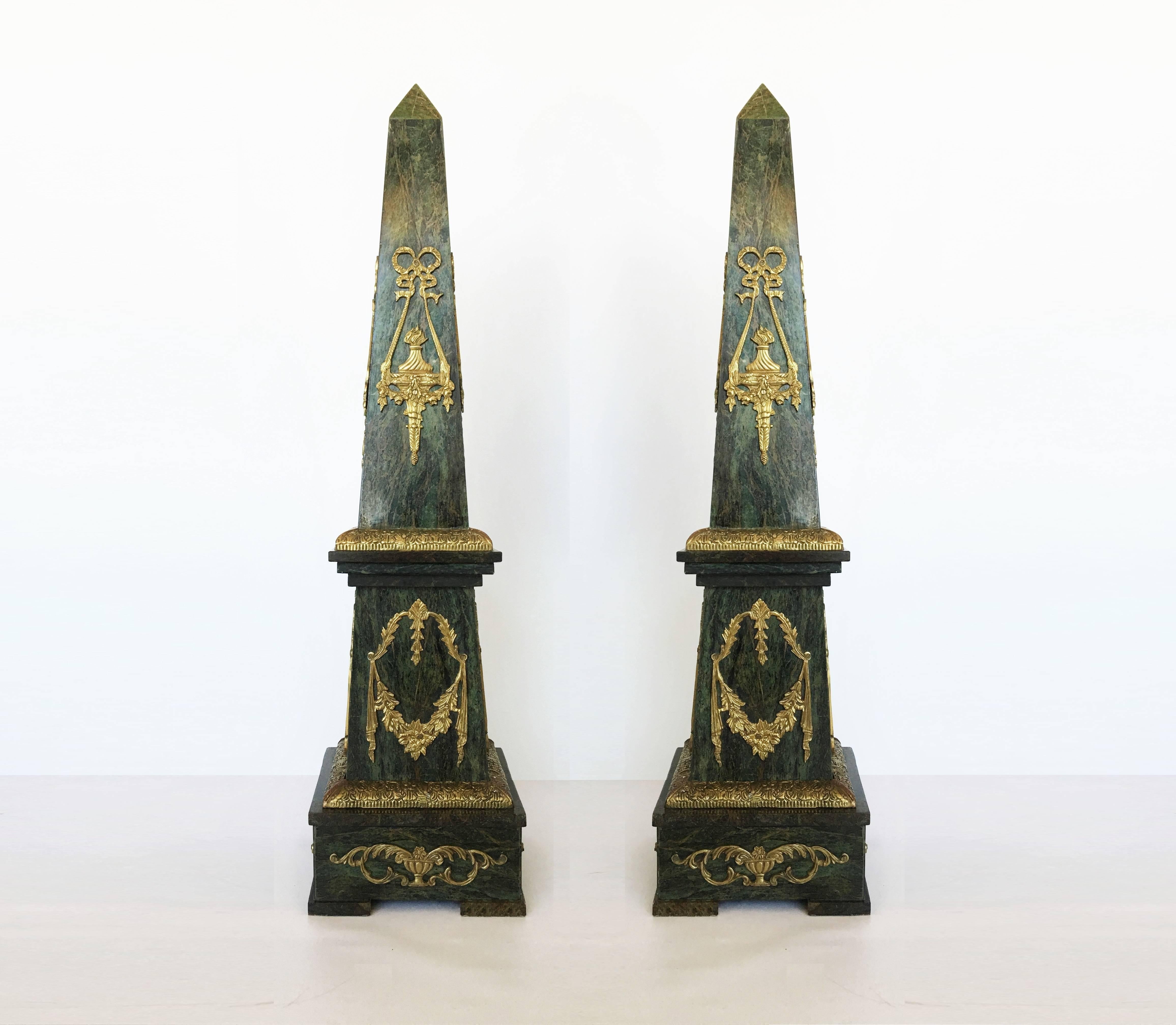 Colossal pair of green marble obelisks with bronze neoclassical style decorative mounts on all four sides. The upper section resembles torchieres, the central section has floral swags and the base has acanthus draped urns.