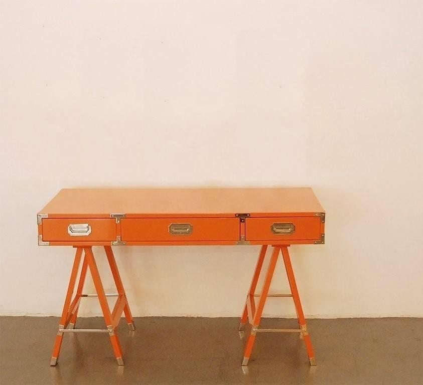 Meticulously restored Campaign Desk on Trestle style sawhorse bases with polished brass hardware. This piece has been refinished in orange lacquer and its hardware has been freshly polished and lacquered. This exceptional quality piece is finished
