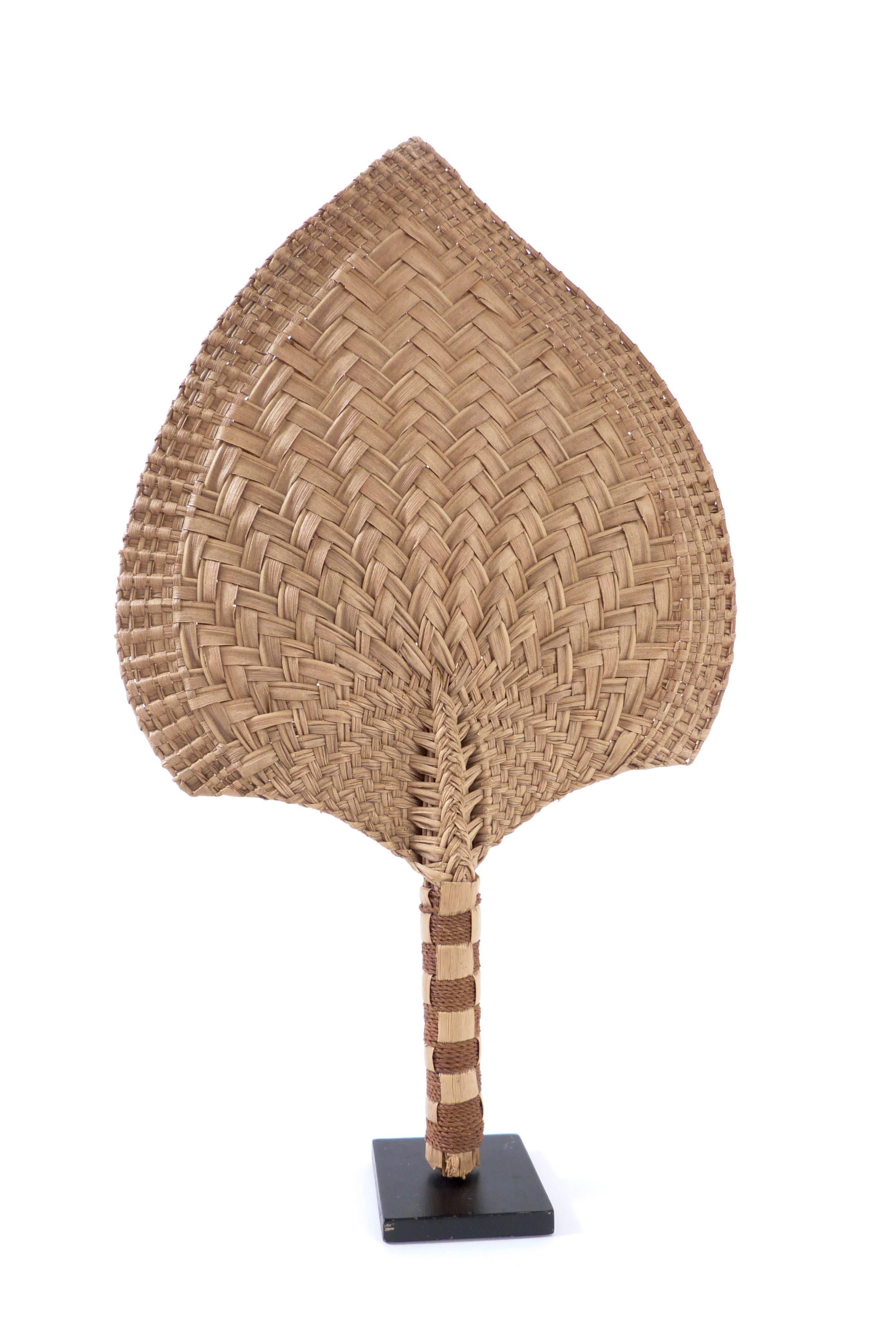 A Tongan palm leaf fan in two colours with a sennit bound handle 38cm high. Provenance, The Melanesian Mission. Founded in 1849 by George Augustus Selwyn. The work of the Mission was primarily centred in Solomon Islands and Vanuatu, but did have