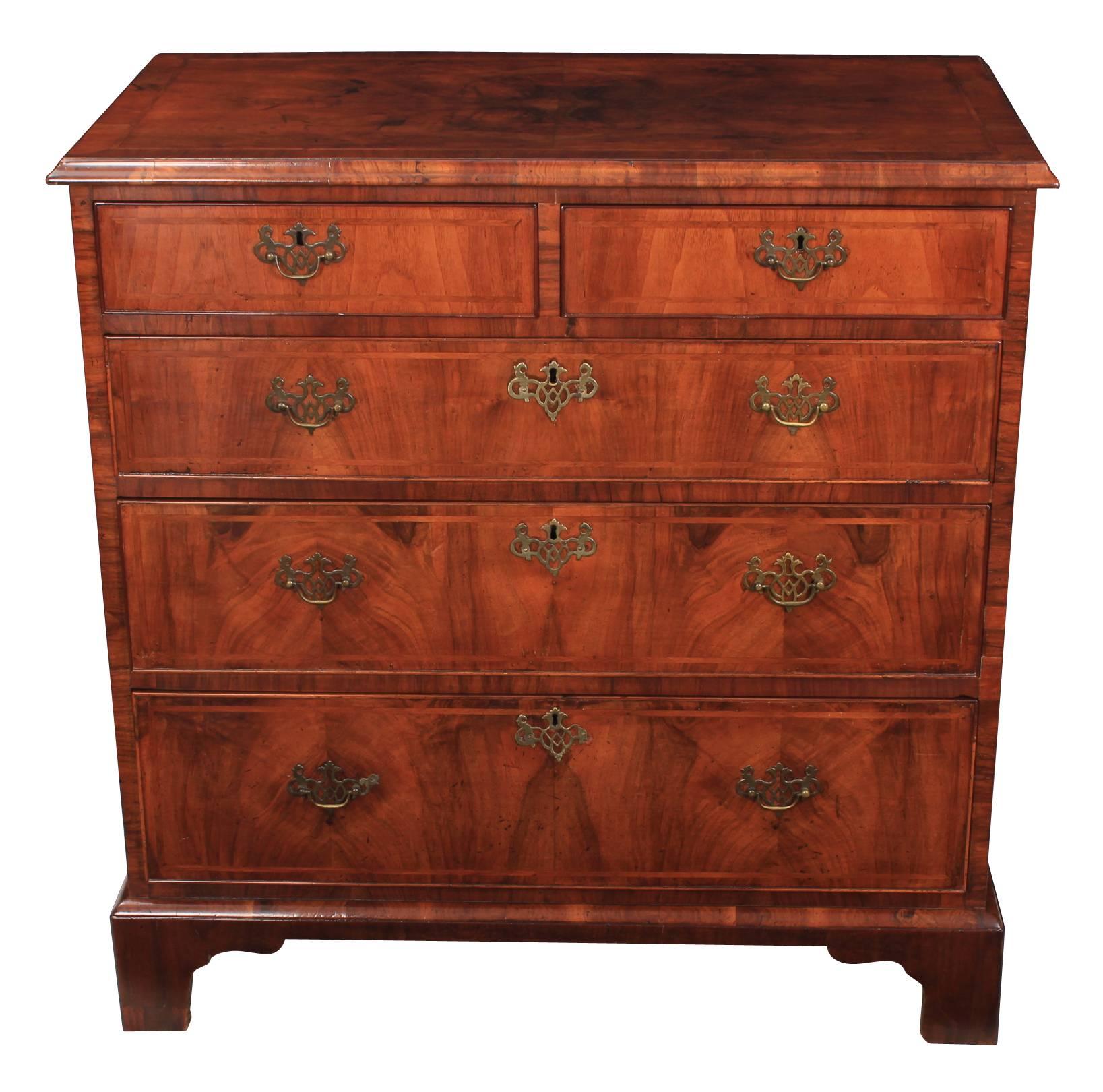 English, circa 1710.
This Queen Anne chest of drawers is offered in superb condition.
Quarter veneered, cross-banded and feather-banded walnut top over 2 short and 3 long graduated drawers.
The drawers are of solid oak dovetailed construction