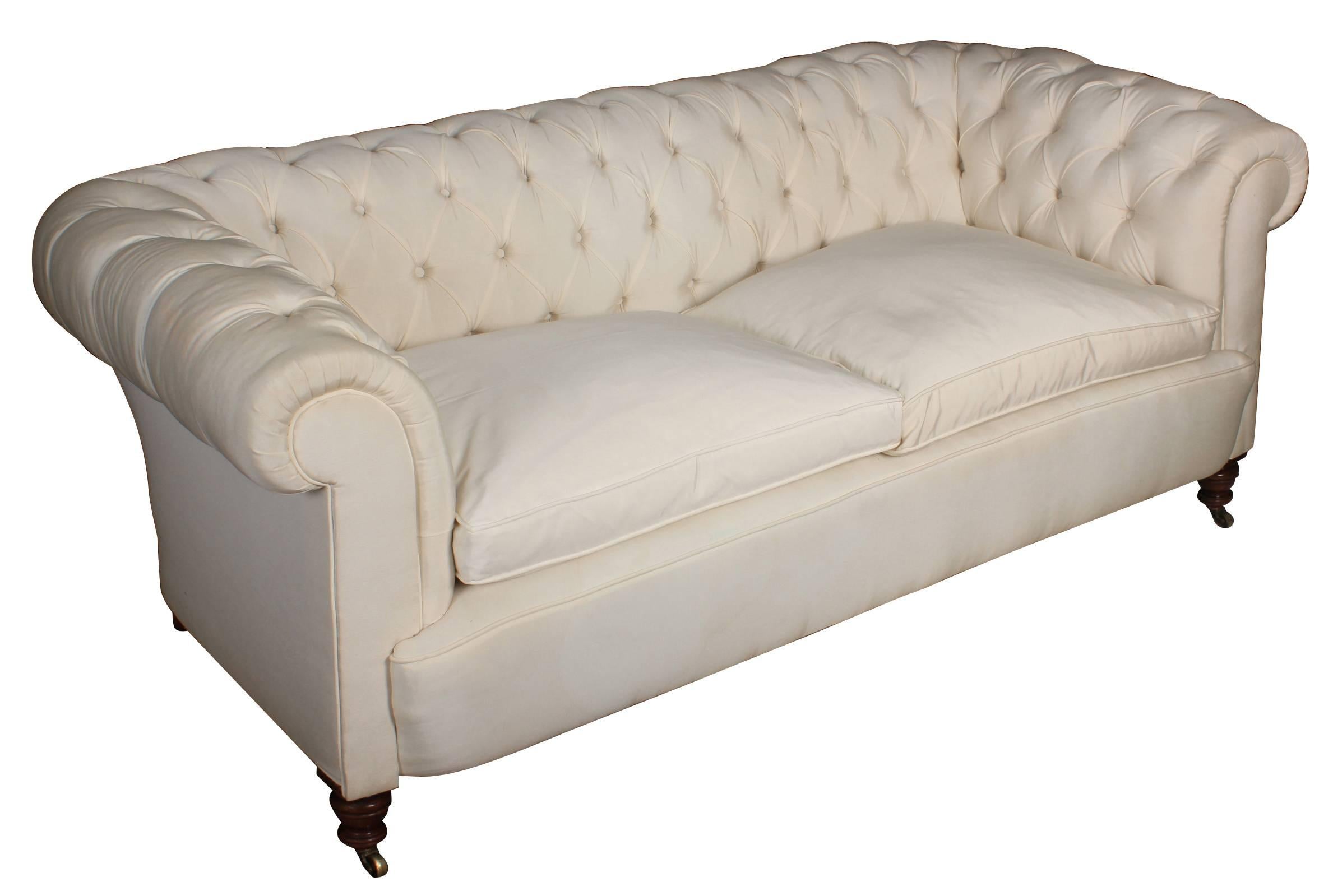 English, Circa 1850.
A lovely Victorian chesterfield sofa upholstered in a pale cream silky fabric, with deep buttoned back and arms and loose seat cushions.
On fantastic turned mahogany legs with brass casters.

L 205cm/80.5
