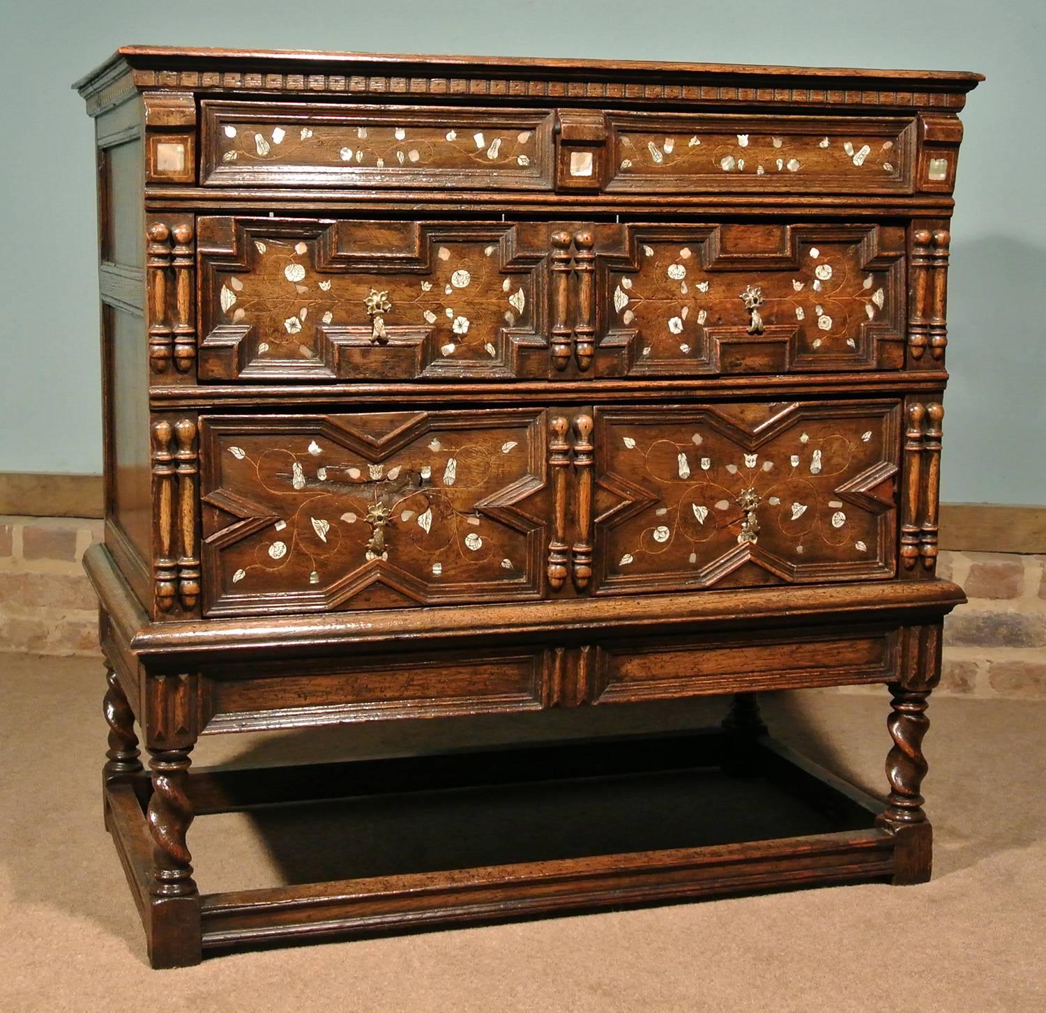 An extremely rare and beautiful oak and elm chest on original stand with original brass drop handles with snaped fittings.

Original elm planked back and drawer linings, full oak carcase and Stand. The drawer fronts with inlaid mother-of-pearl and