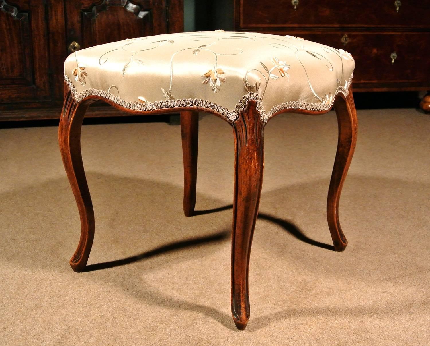 Of excellent color and condition, a very elegant 18th century solid walnut stool.

Beautiful serpentine solid walnut seat rails and long cabriole legs with rolled channel carved borders and scrolled peg toes in the French manner.

The legs