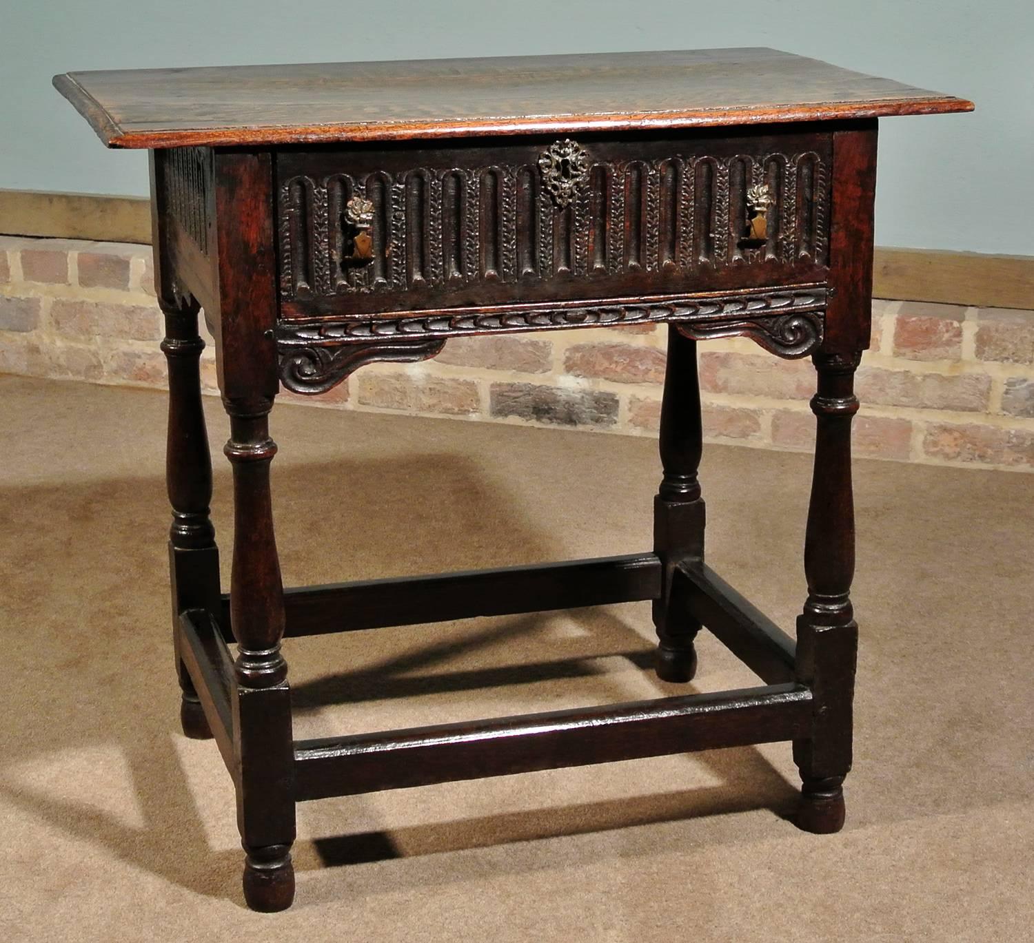 An early and most attractive solid oak lowboy, circa 1630 with a lovely color and retaining its original three plank top with shapely border.

The well turned legs with some old bruises and dings and slight wear to the very tips of the feet