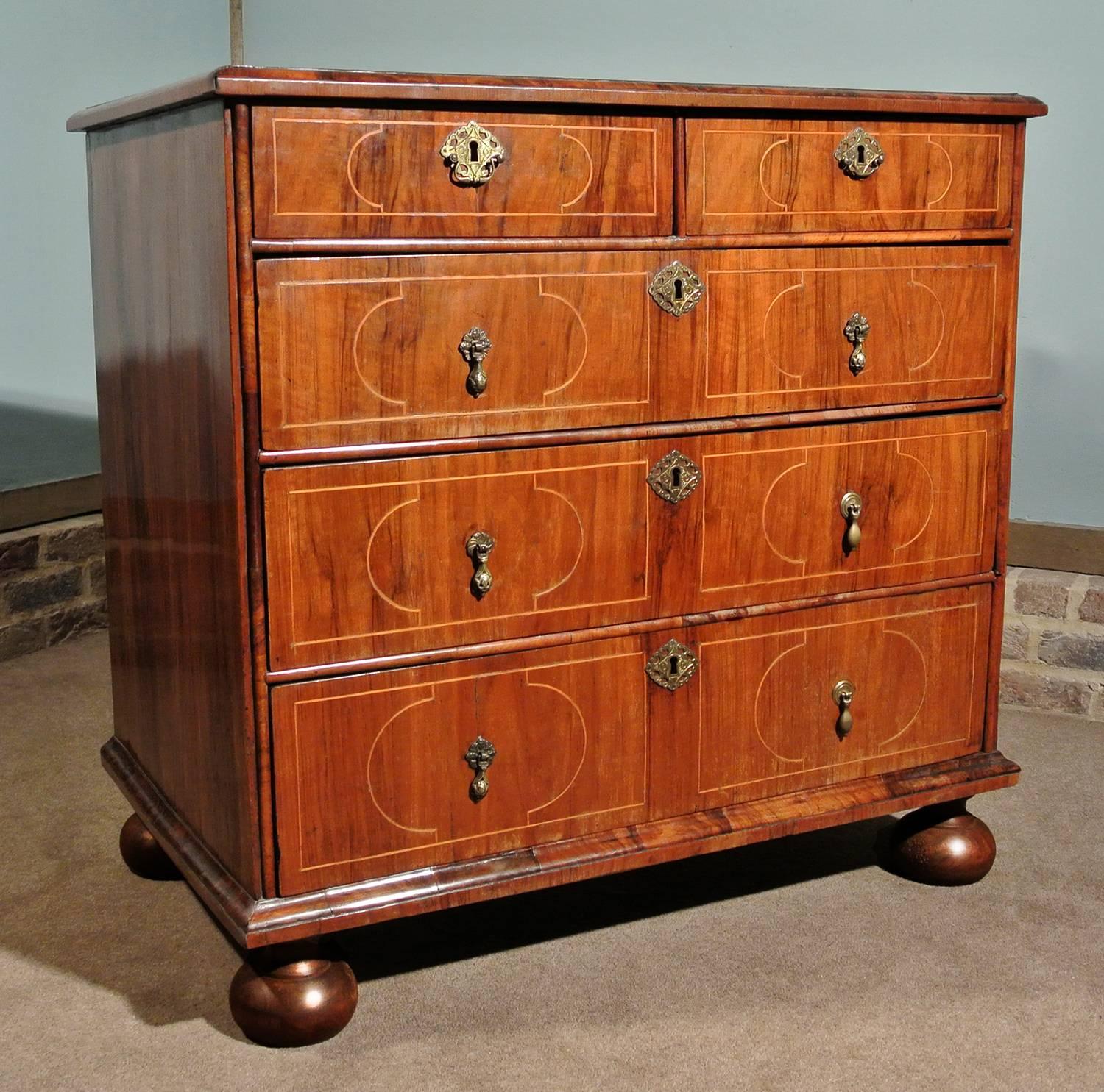 A very handsome walnut chest of drawers made by hand in circa 1700. The chest is solid oak and dressed with beautiful, and very thickly cut, walnut veneers inlaid with boxwood stringing in excellent original condition and with a warm rich color and