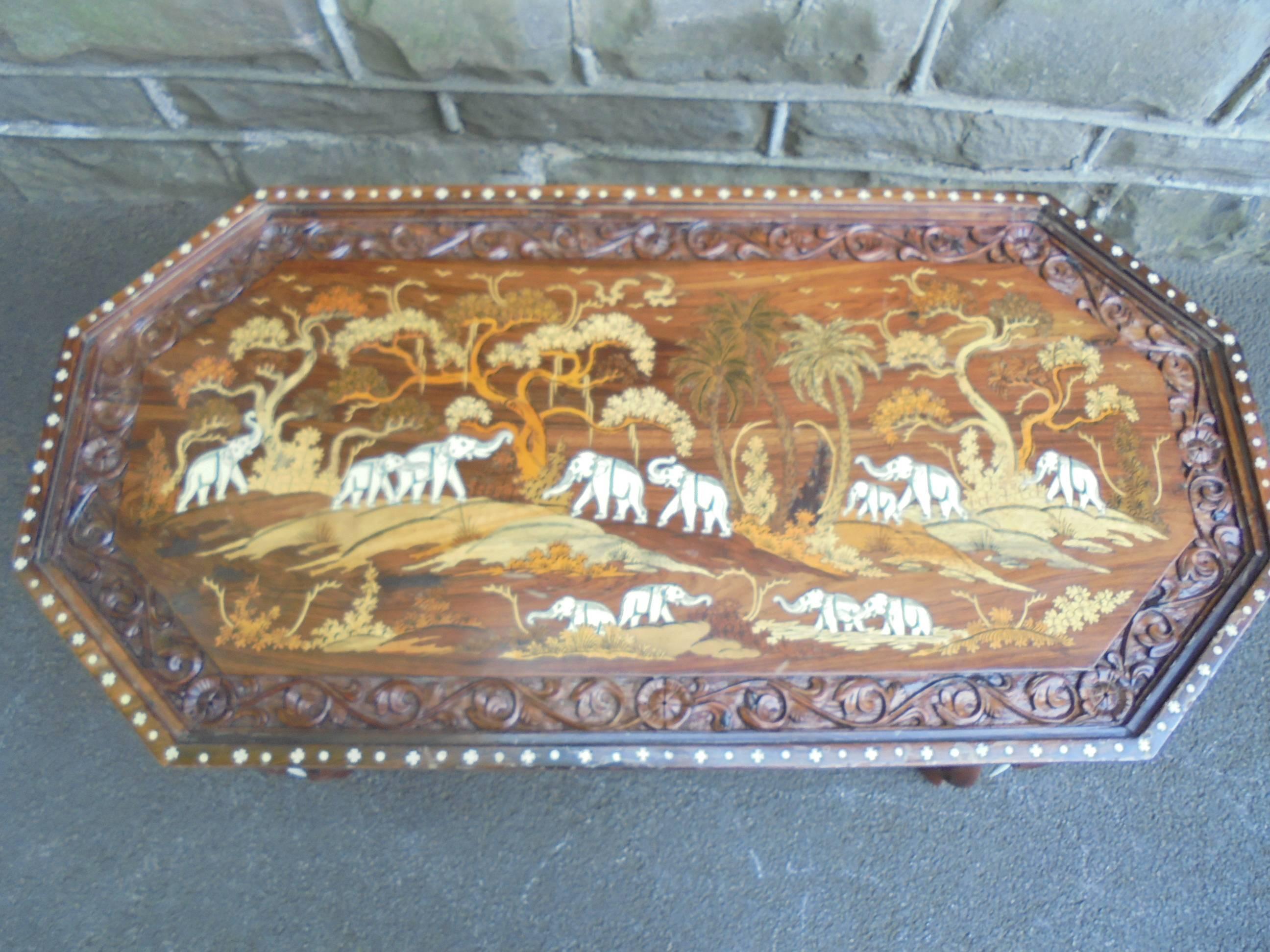 Offered for sale is this very decorative antique Anglo-Indian coffee table.

Dating from 1900-1910. Indian rosewood, inlaid decorative scene to the centre, ivory, boxwood, carved broder. Standing on ornate carved elephant legs with ivory tusks.
