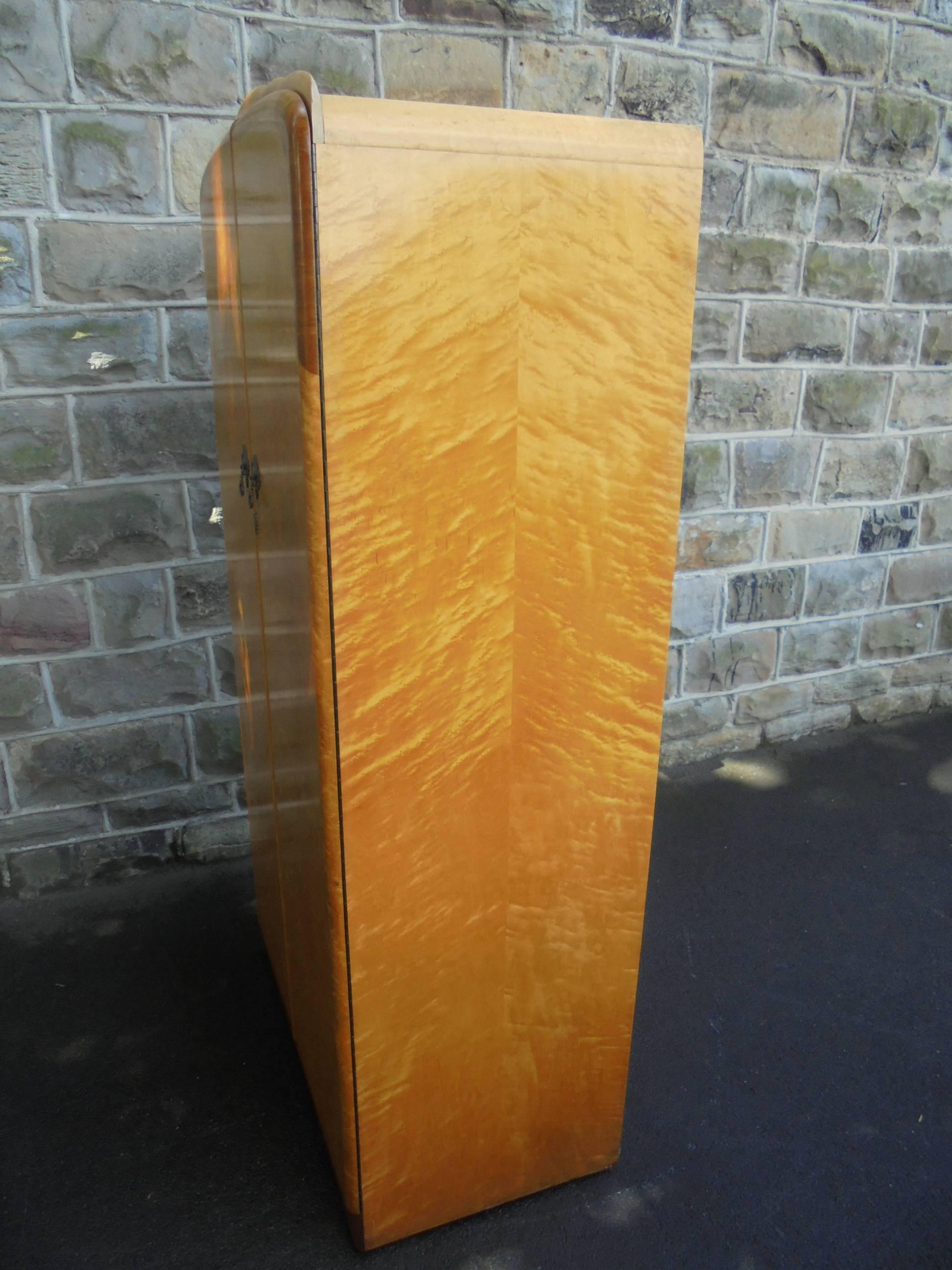 Offered for sale is this Art Deco bird's-eye maple wardrobe armoire. Part of a large bedroom suite we have to offer.

Dating from 1930. Nice design, veneered in bird's-eye maple with walnut trim to the top and plinth. Pair doors, inside there are
