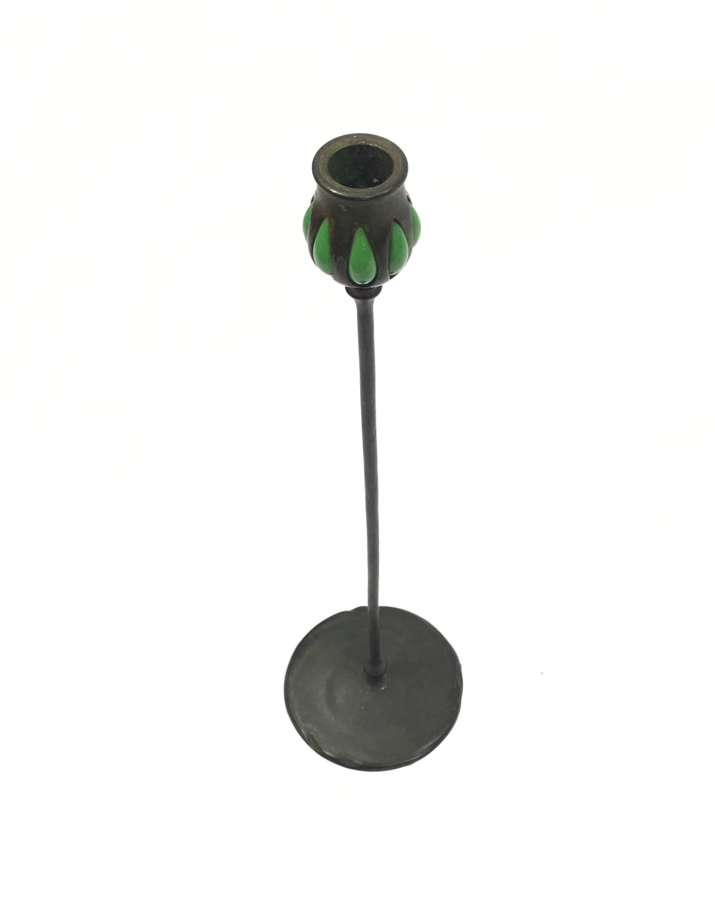 The bronze candlestick is signed Tiffany Studios, New York. The pierced bronze portion has handblown green glass with inspiration of nature. It is numbered 5393.