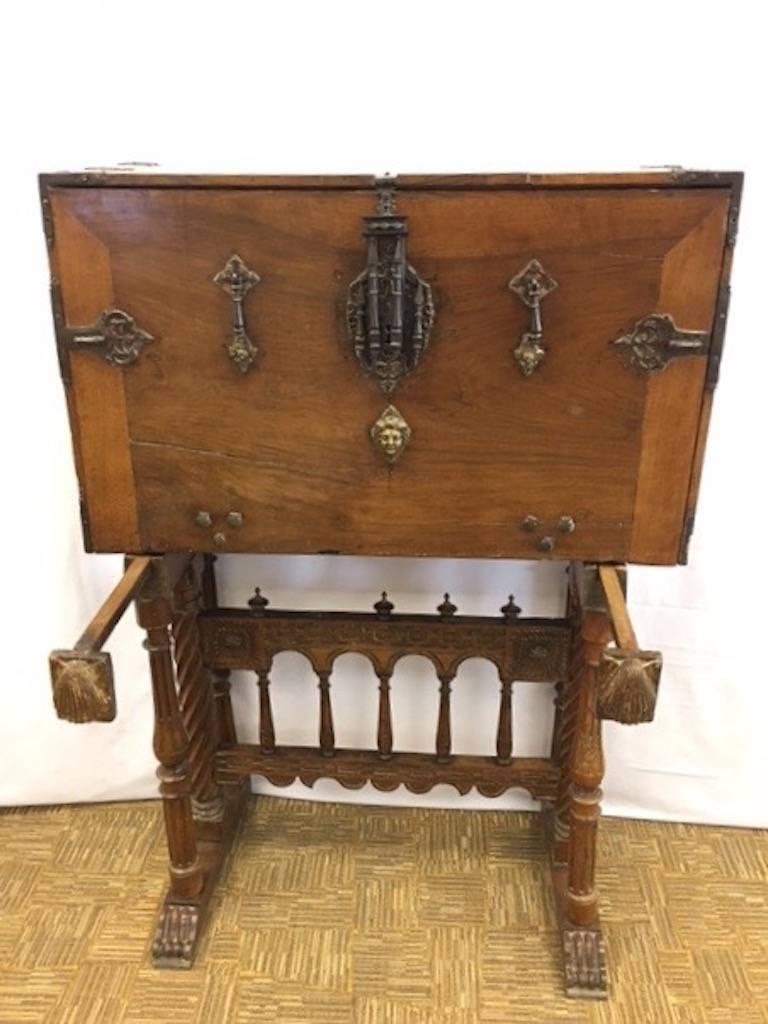 This vargueno or traveling desk is comprised of a chest with fold down front that sits atop a carved walnut stand. They are two separate pieces. The cabinet is walnut with bone inlay and features hand-forged iron work all from the 18th century. The