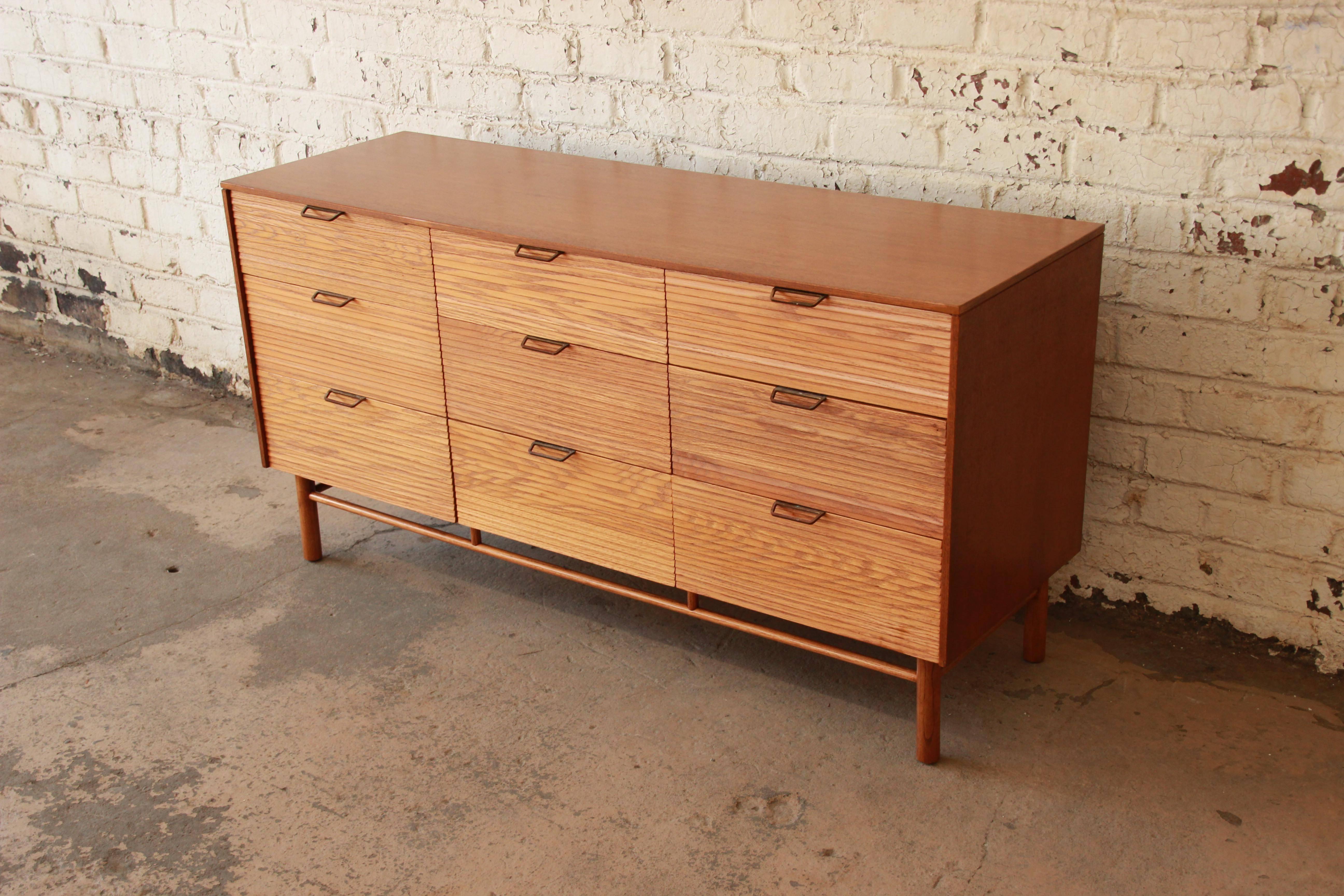 Two-toned Mid-Century Modern dresser by iconic designer Raymond Loewy for Mengel Furniture. The dresser features a unique louvered front and offers ample storage with nine deep drawers. A unique Loewy design, the dresser is finished in two tones,