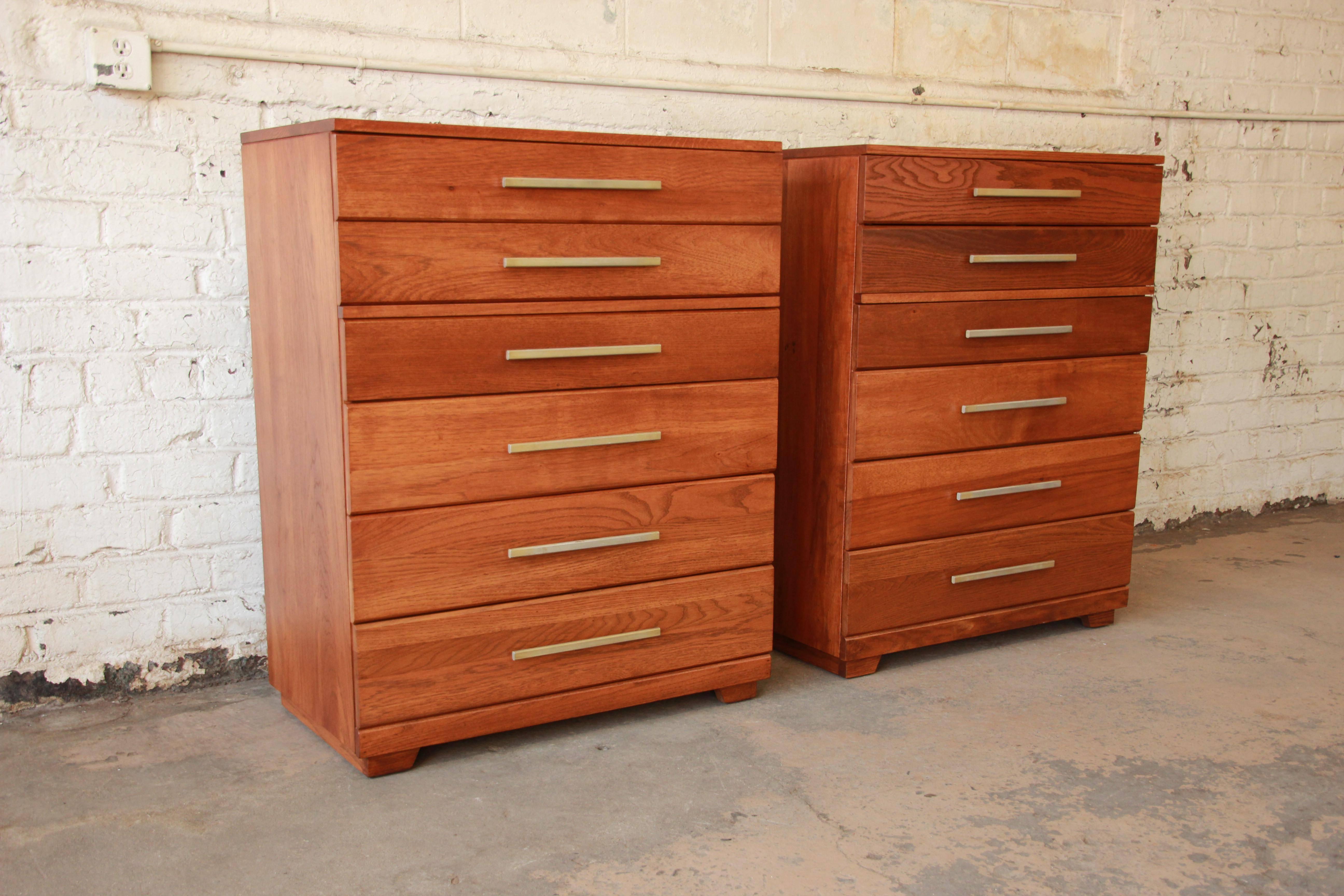 Exceptional pair of Mid-Century Modern solid oak highboy dressers by iconic designer Raymond Loewy for Mengel Furniture. These minimalist dressers feature clean, sleek Mid-Century lines and beautiful wood grain. The aluminum drawer pulls are
