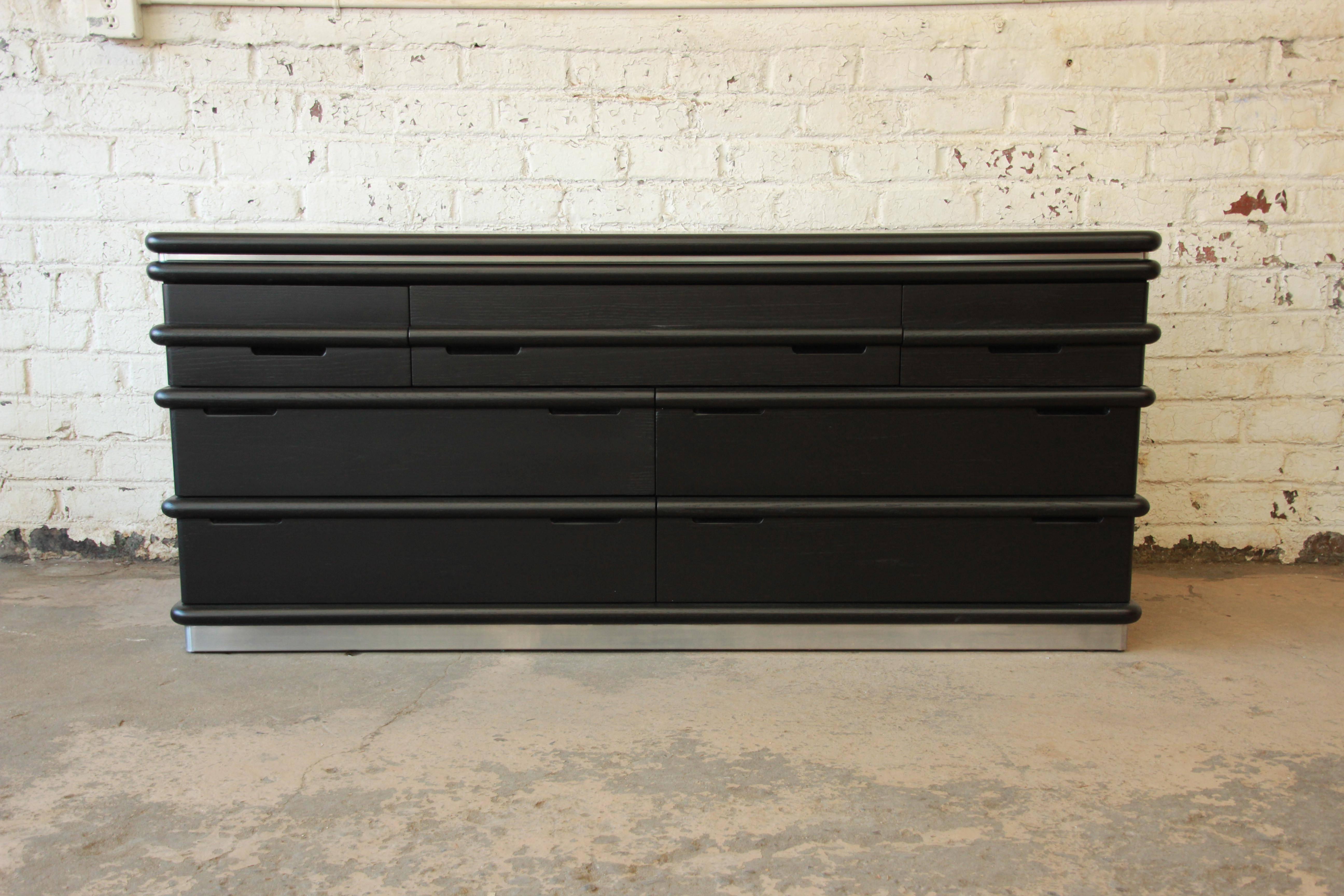 Refinished in black lacquer solid oak and chrome dresser designed by Jay Spectre for Century Furniture. The dresser features an attractive cerused finish, as well as carved rounded borders and chrome bands at the top and bottom. The dresser is well