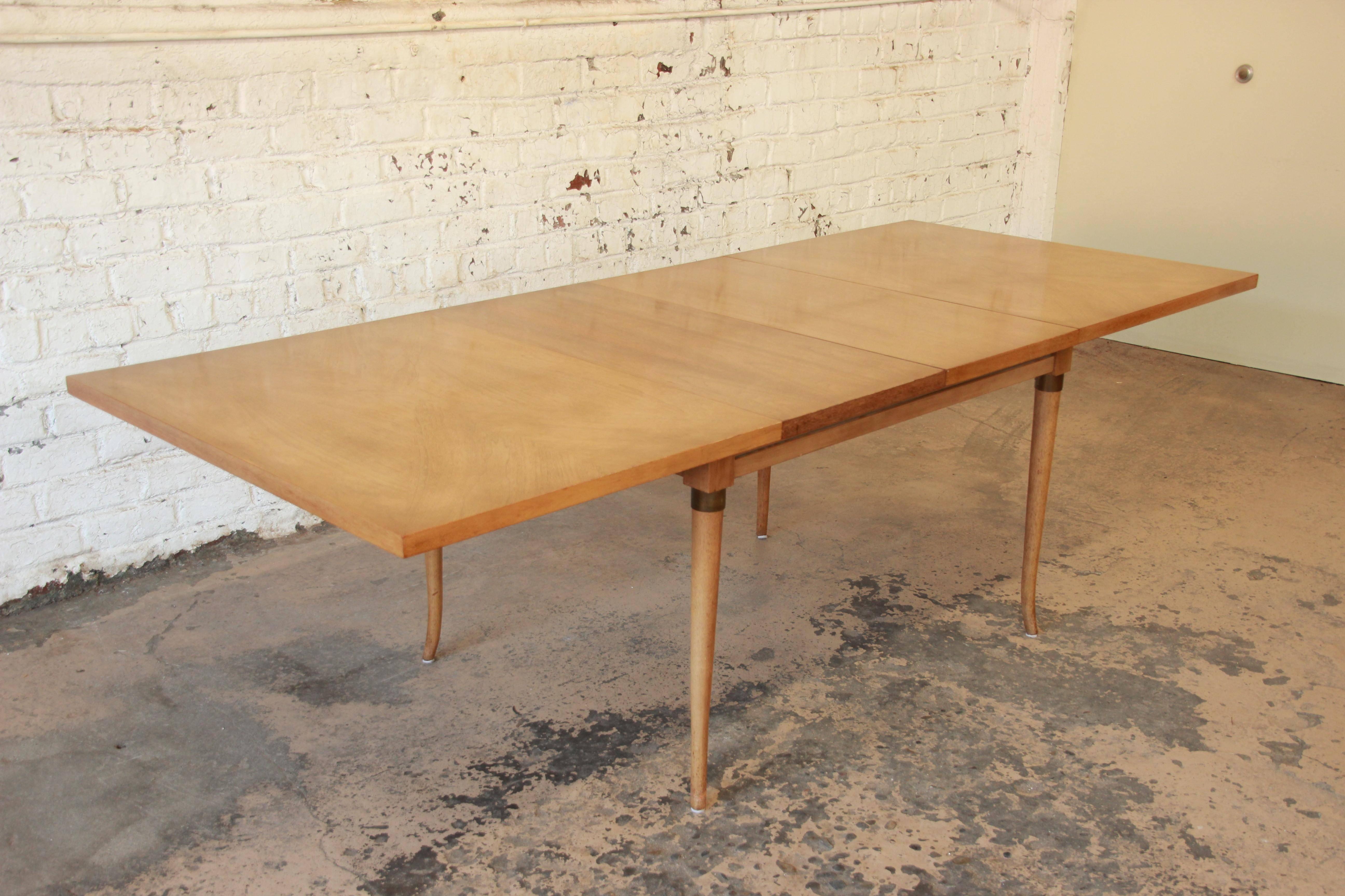 A beautiful Mid-Century Modern bleached walnut extension dining table designed by Merton Gershun for American of Martinsville, circa 1960s. The table features beautiful wood grain, nice brass details, and a sturdy 1.5