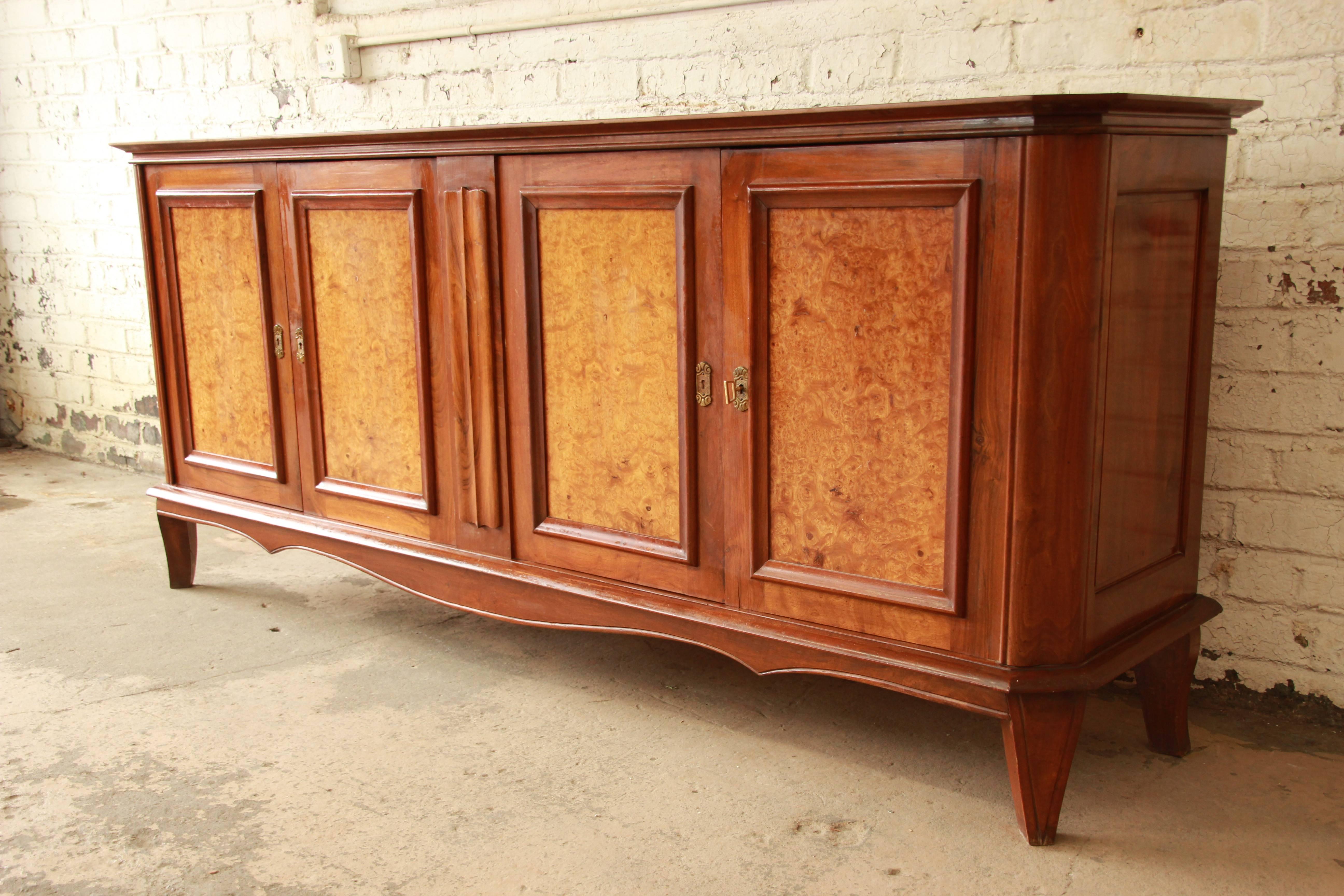 Offering an exceptional 1940s French sideboard or buffet. This monumental piece features beautiful burled maple doors, solid wood construction, and an inlaid diamond design on the top. It offers ample room for storage, with two dovetailed drawers