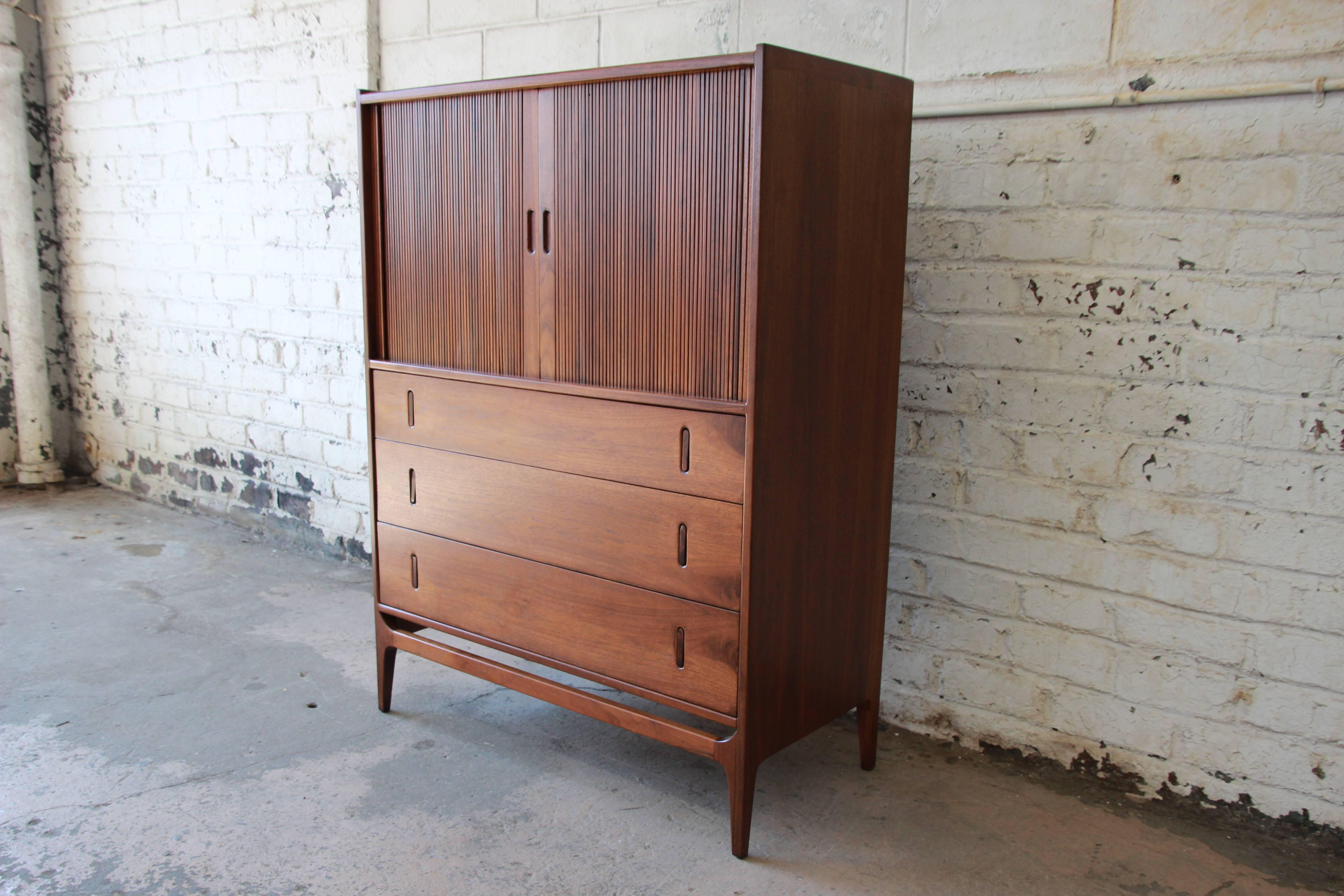 Beautiful highboy dresser with tambour doors by Richard Thompson for Glenn of California. The dresser has been newly restored and refinished. The solid walnut legs rise up to a stretcher across the front section. Above are three drawers with solid