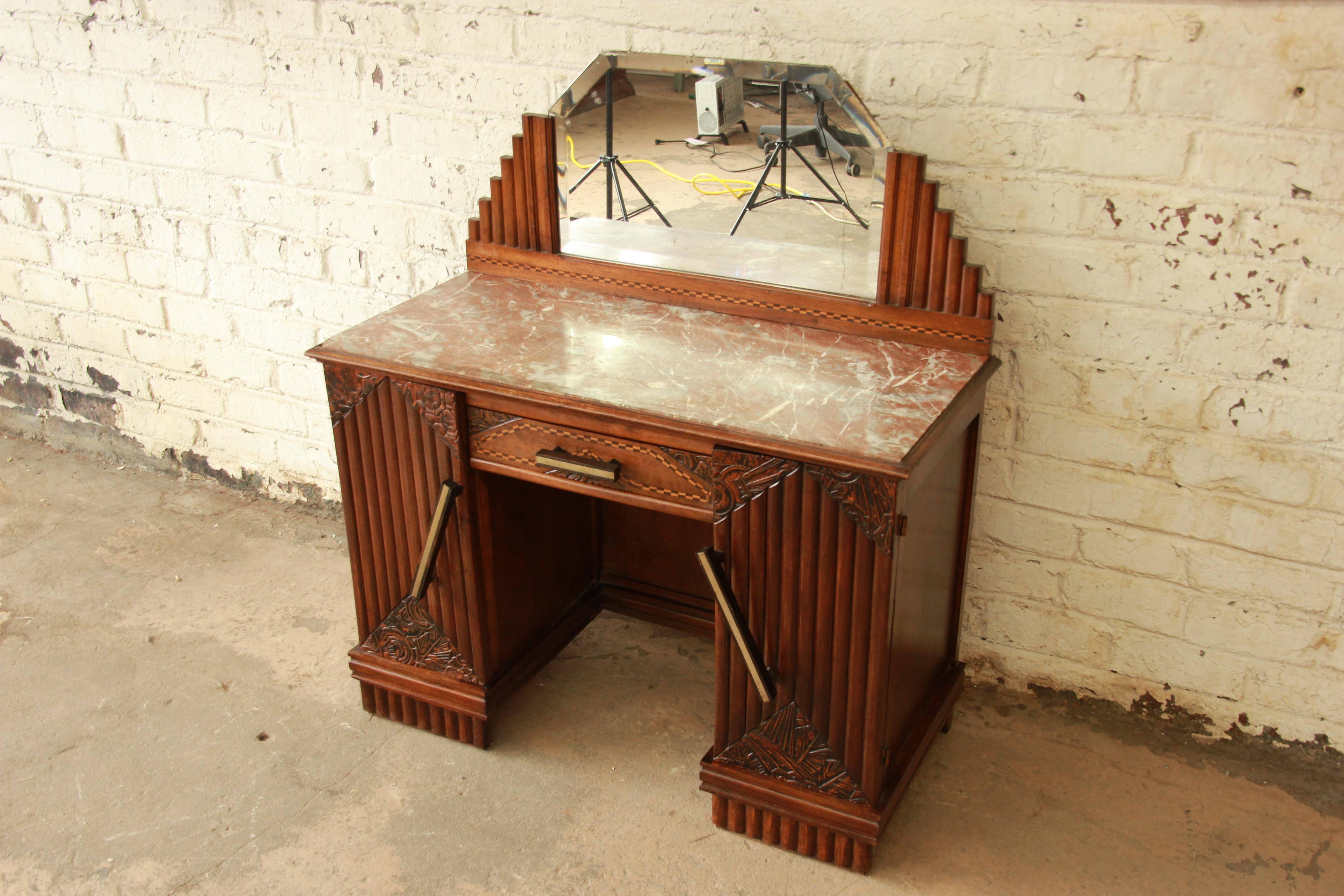 Exceptional 1930s French Art Deco marble-top vanity. The vanity features gorgeous hand-carved details, a beautiful inset marble top, and a beveled mirror. It is very well constructed from solid walnut, with dovetail joints. There is one very small