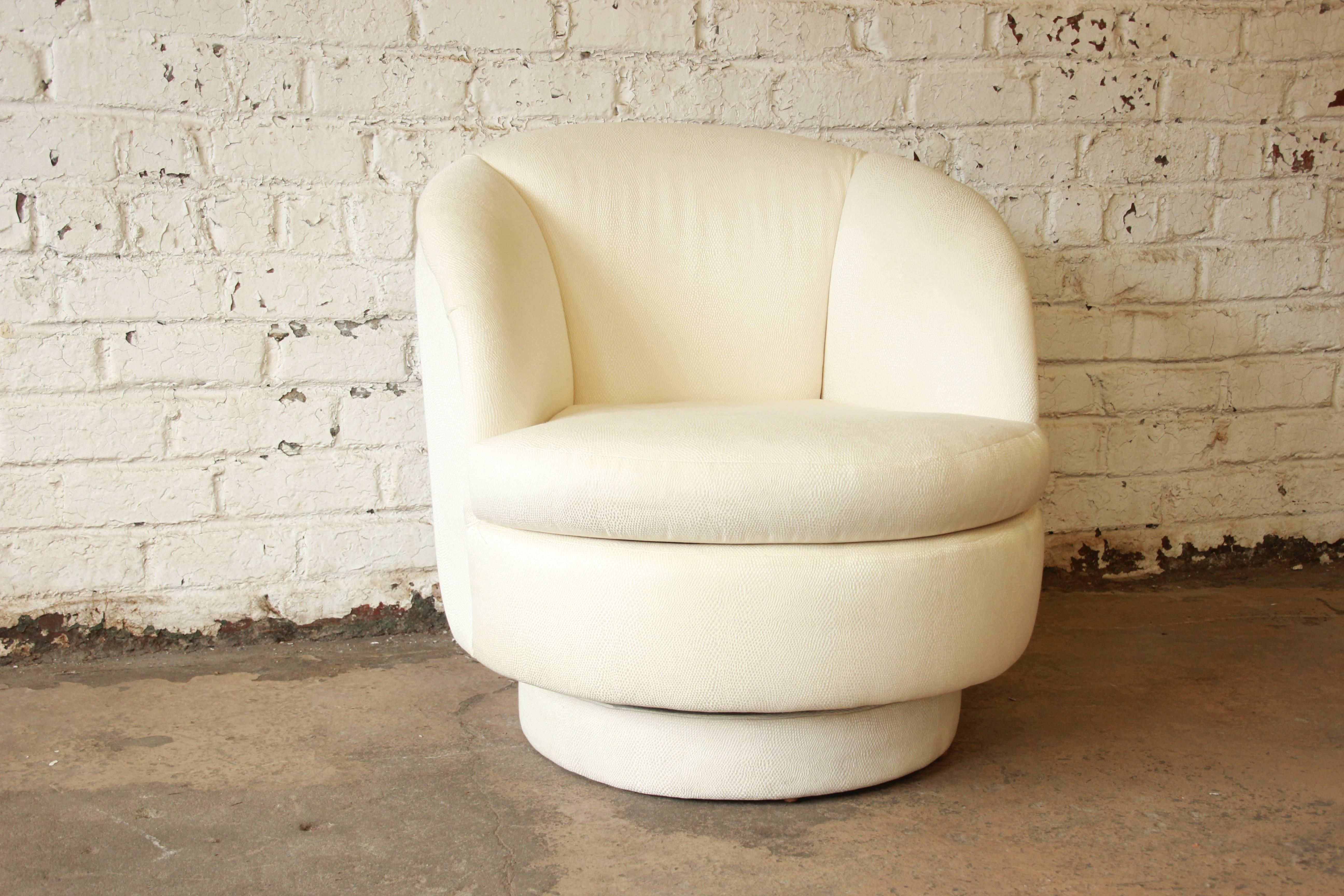 A beautiful swivelling barrel back club chair designed by Milo Baughman for Thayer Coggin, circa 1980s. The chair features a swivelling base and original ivory upholstery. Original label is present. The chair is in excellent condition.
 