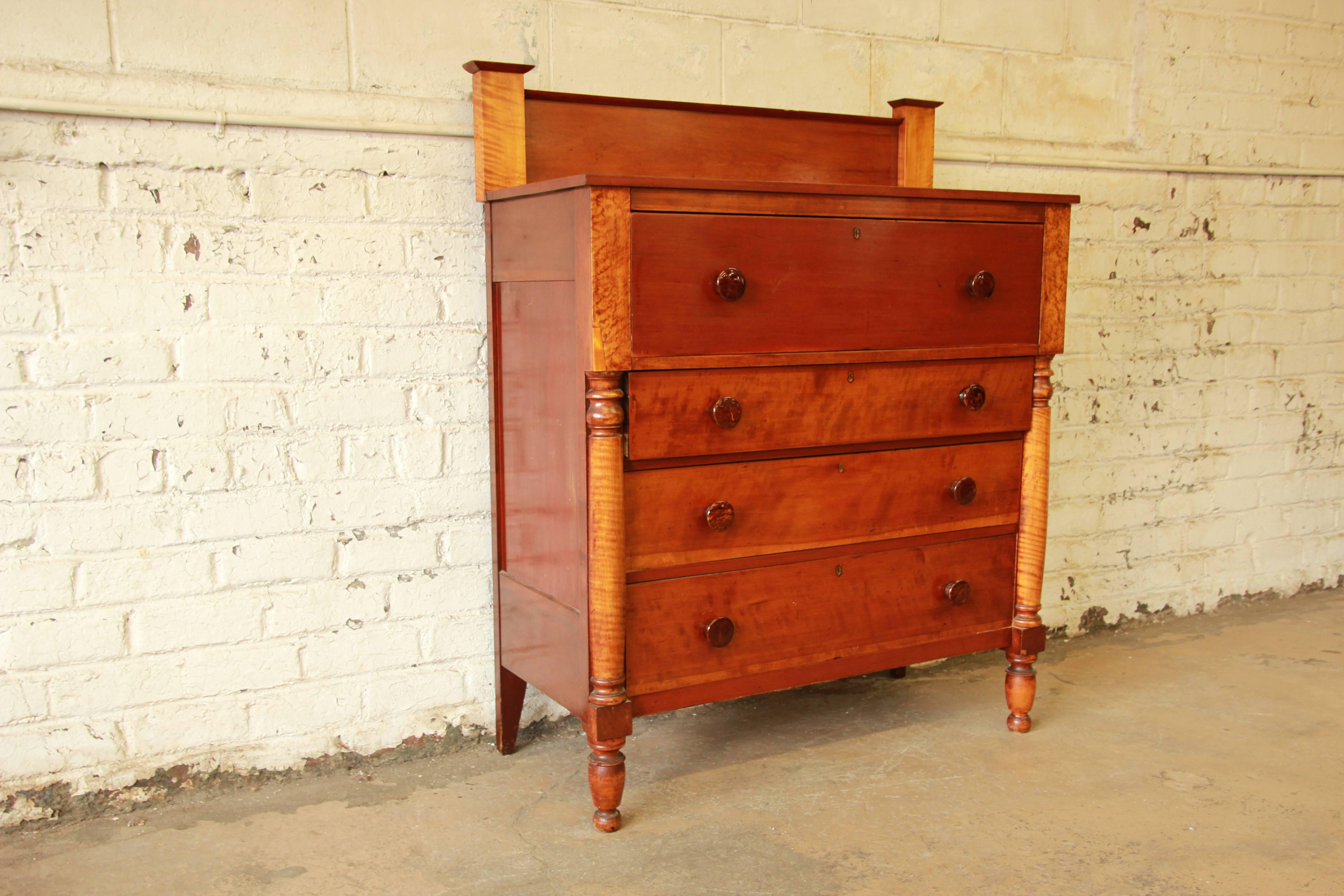 A beautiful American Sheraton four-drawer chest of drawers, circa 1820. The dresser is made from solid cherry, with gorgeous tiger maple columns. Made in the early 19th century, the dresser is very well constructed and has dovetail joints. The