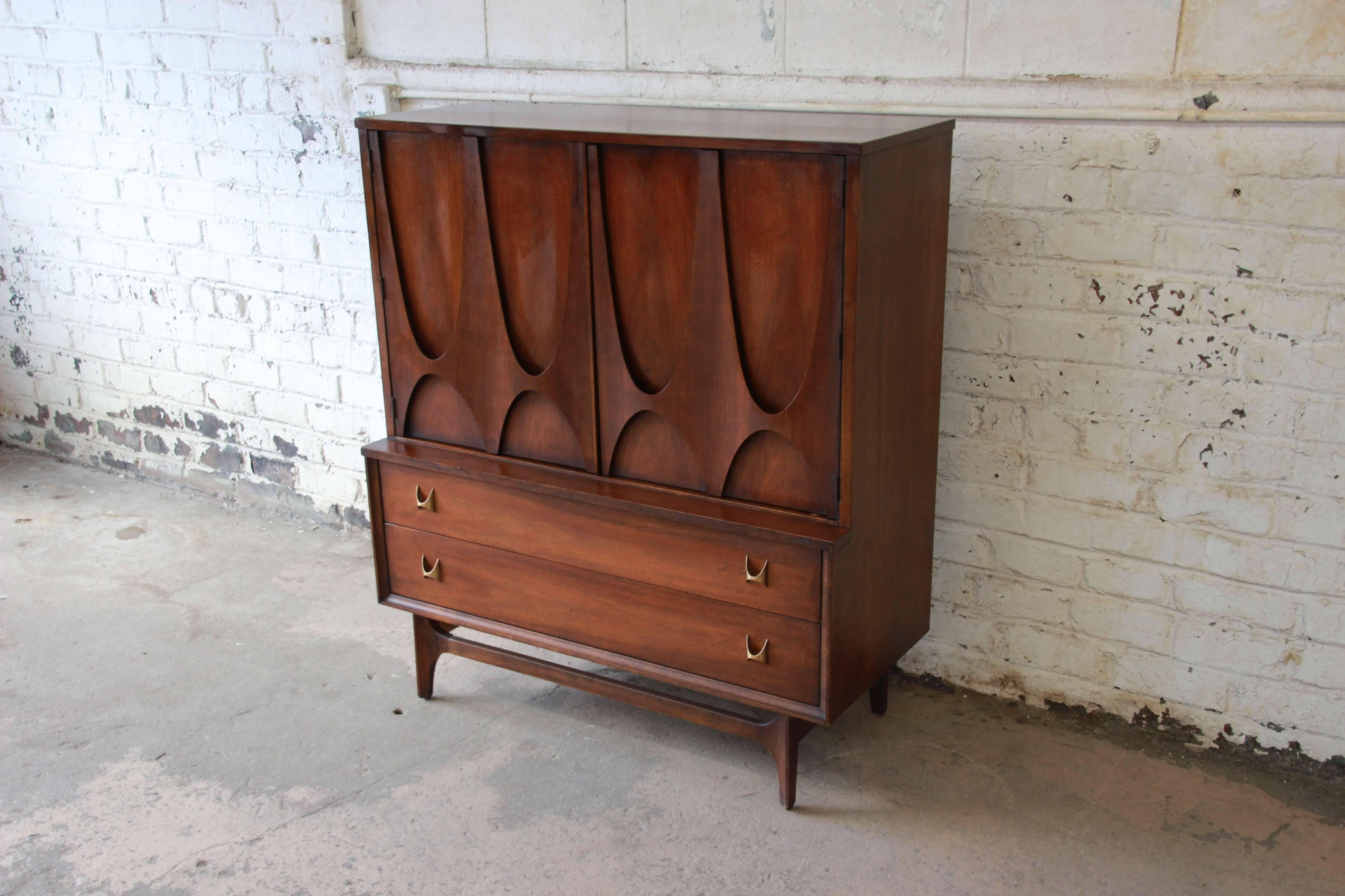 Offering the iconic designed Broyhill Brasilia gentlemen's chest designed by Oscar Niemeyer. The chest has sculpted arches and original pulls. The two large cabinet doors open up to four drawers on the left side and several shelves on the right