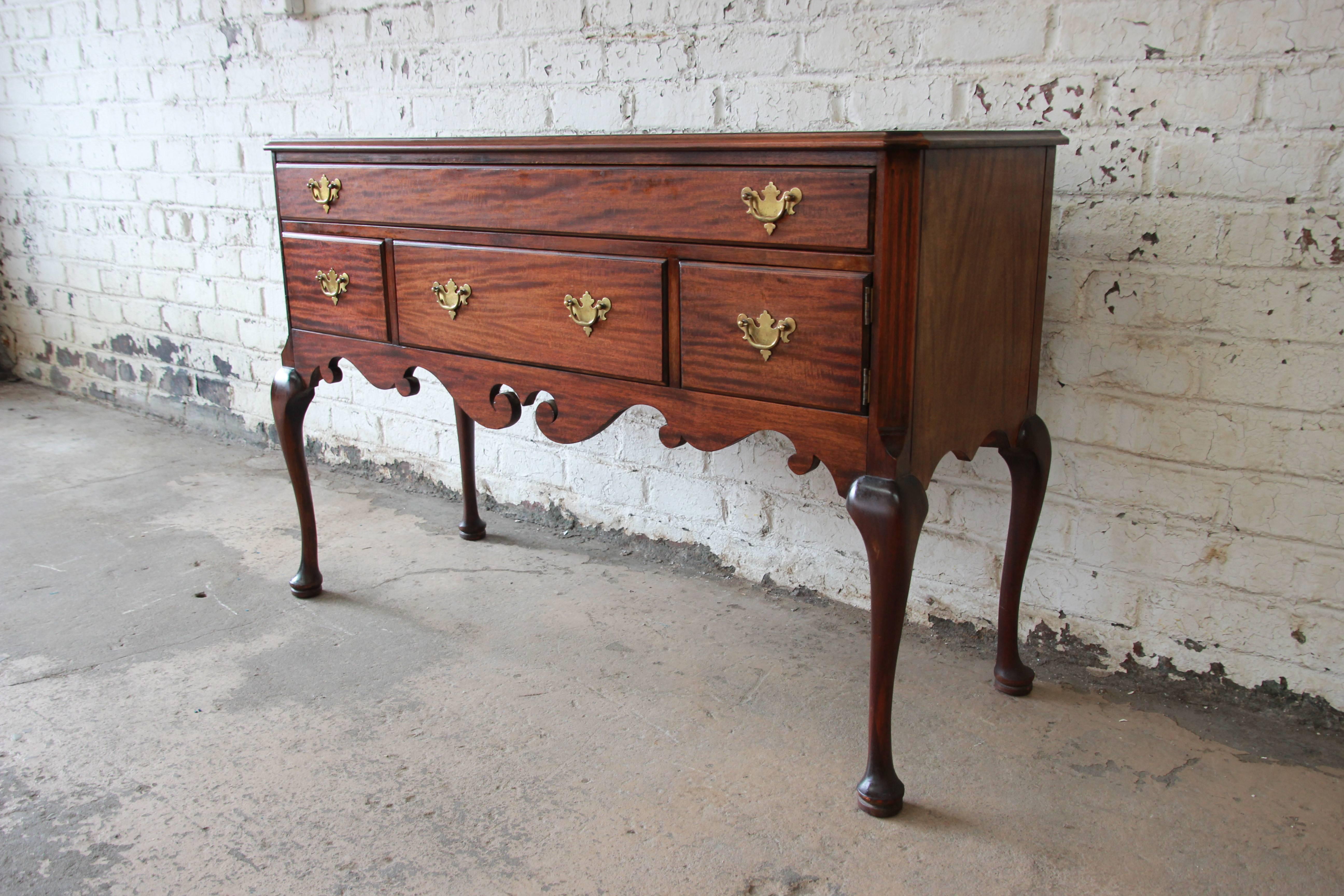 A beautiful Queen Anne style mahogany sideboard or server by Baker Furniture Company. The sideboard features gorgeous mahogany wood grain and a nice traditional Queen Anne style. It offers ample room for storage, with two dovetailed drawers and two