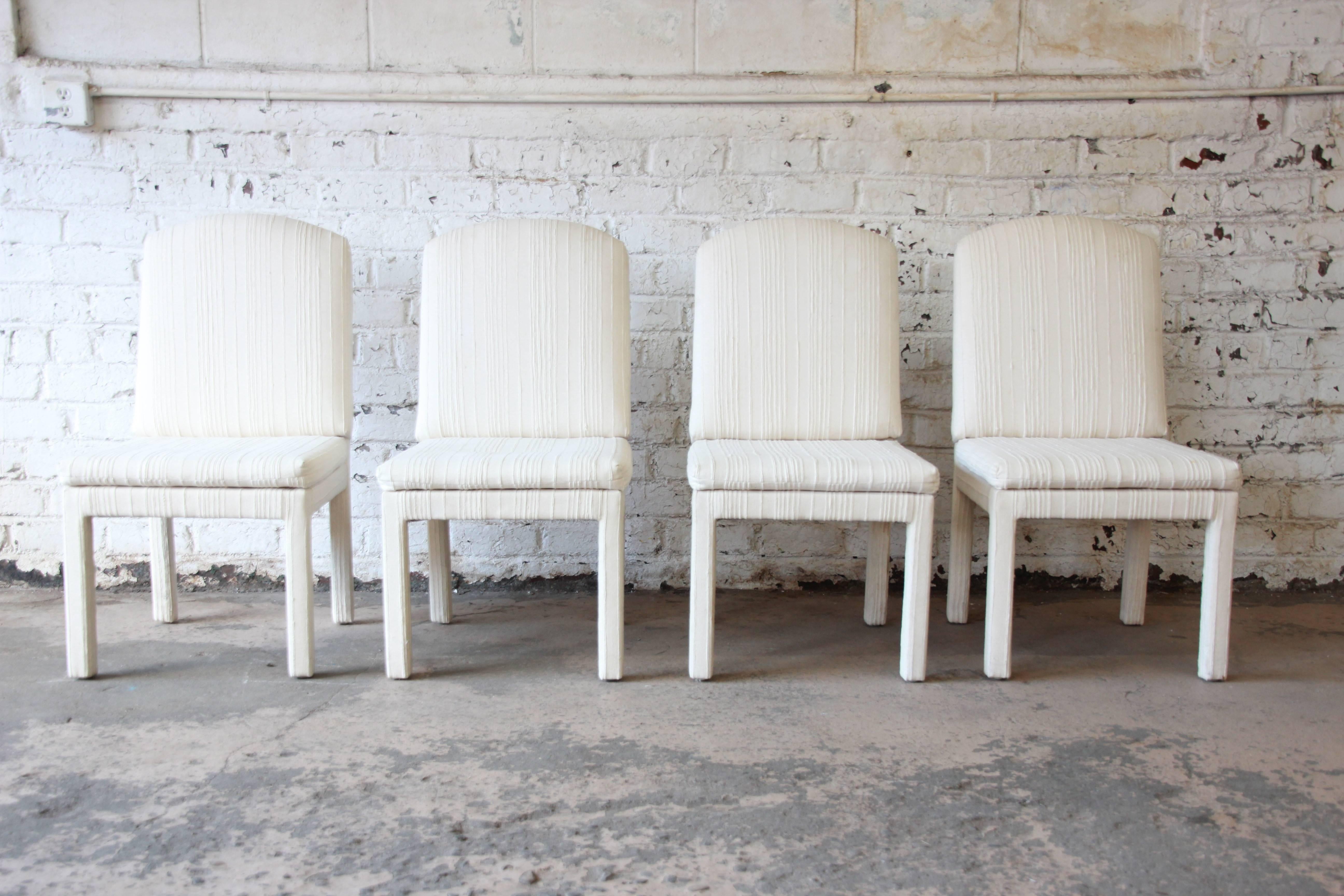A stylish set of four Parsons dining chairs made by Design Institute America in the style of Milo Baughman. The chairs are sturdy and very comfortable. Ivory upholstery is original and in fair condition. Could easily be reupholstered if desired.