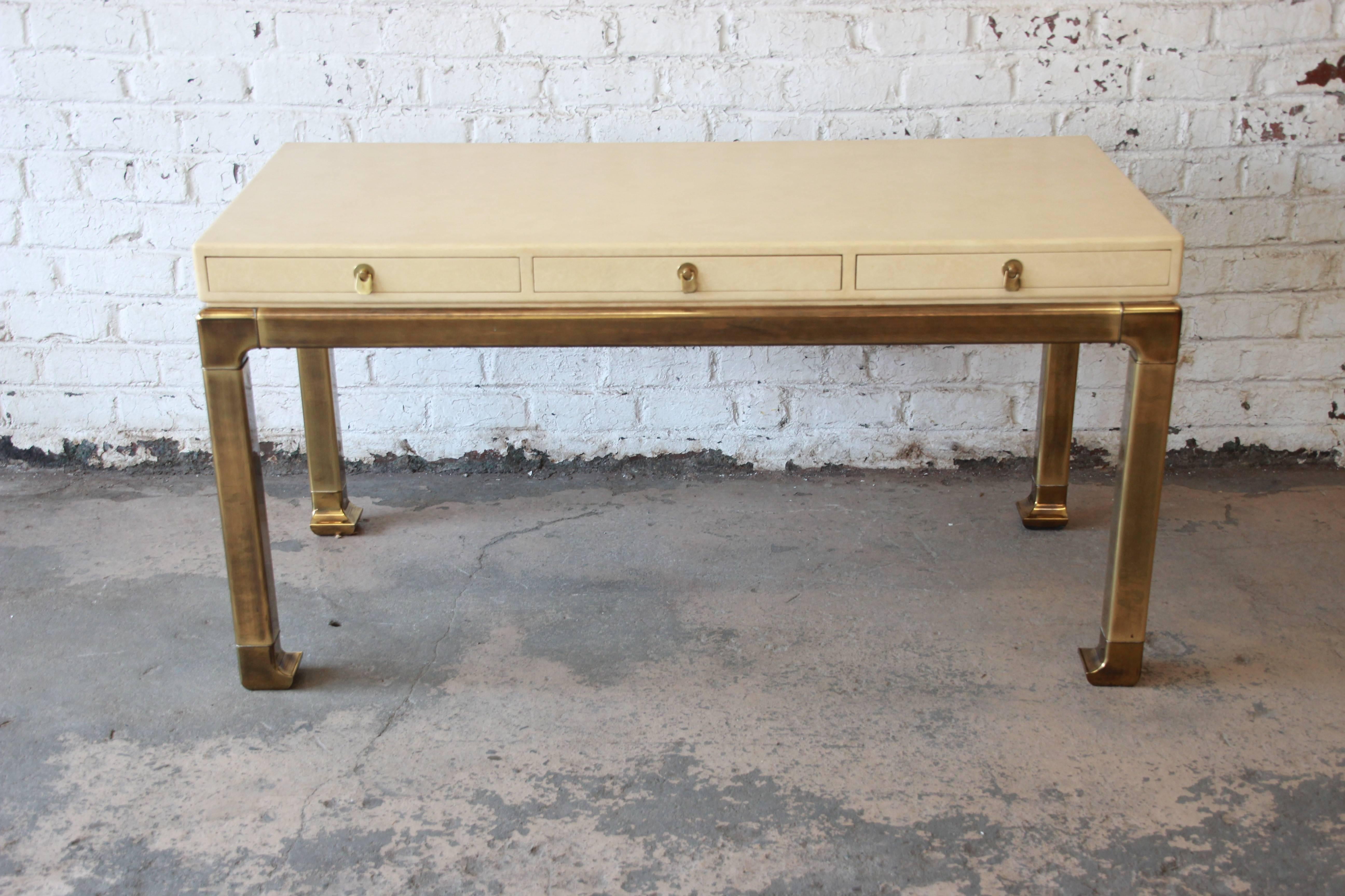 Offering a stunning brass and faux shagreen chinoiserie style desk. The desk has a large writing surface with three drawers with solid brass pulls. The brass legs descend to a nice curved Asian Style foot. This beautiful and rare statement piece