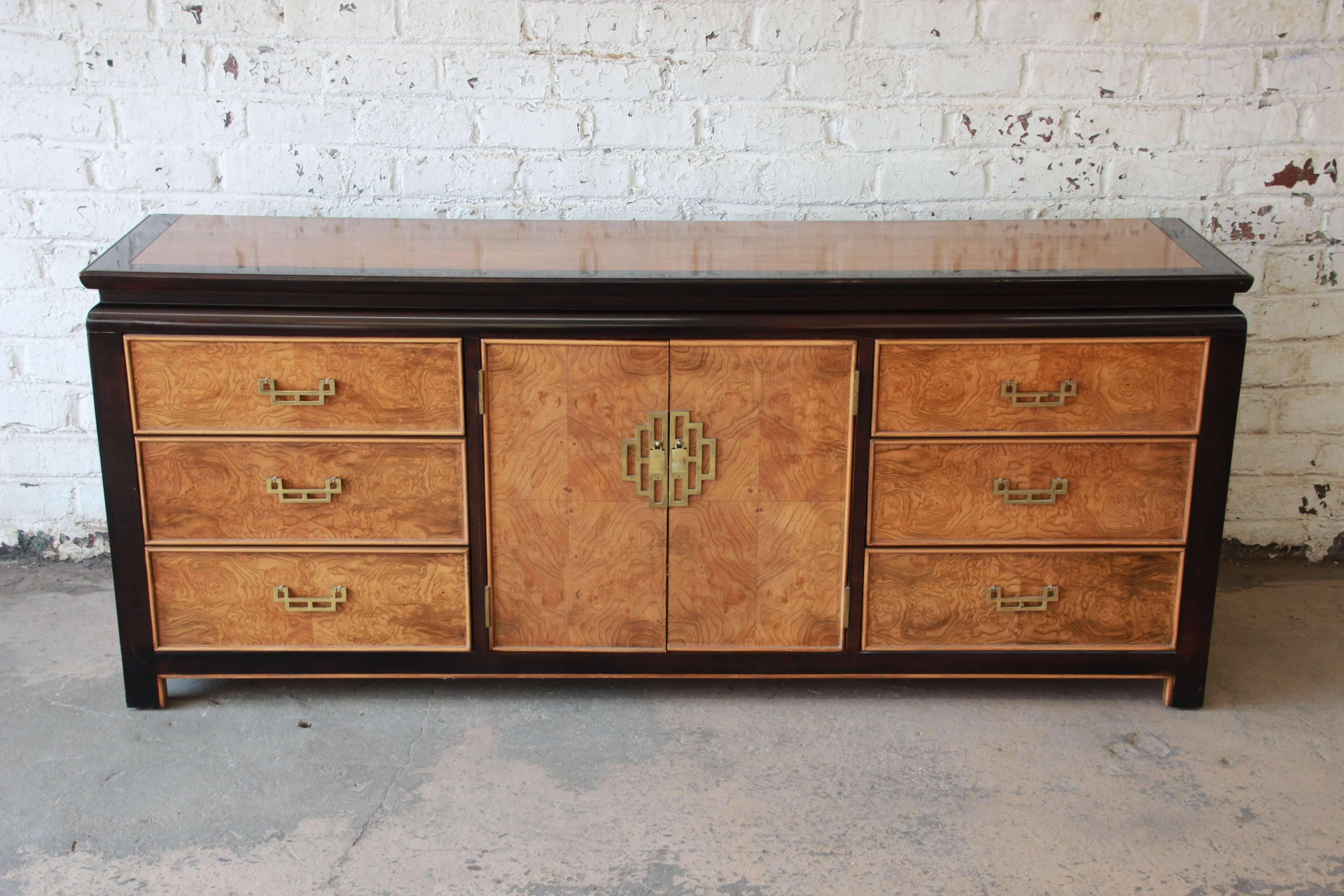 Offering a beautiful burl wood and black lacquered Chin Hua long dresser. The dresser has nice brass hardware and features nine large drawers that offer lots of room for storage. The centre cabinet doors open up to three smooth sliding drawers and