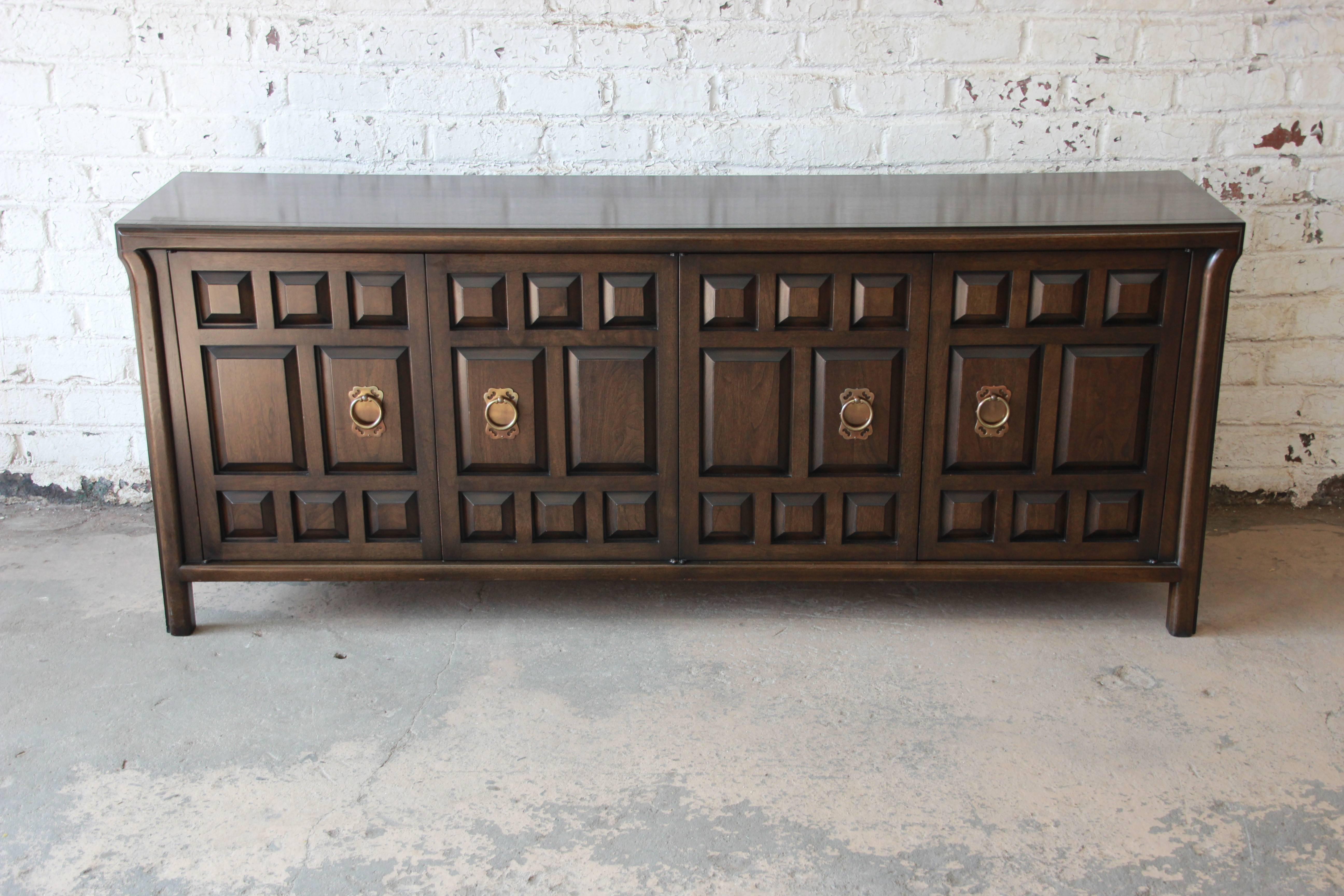 A gorgeous vintage dark walnut Spanish Colonial style sideboard by John Widdicomb. The sideboard features rich walnut grain and a unique Spanish design. It offers ample room for storage, with three deep drawers on the left side and a single