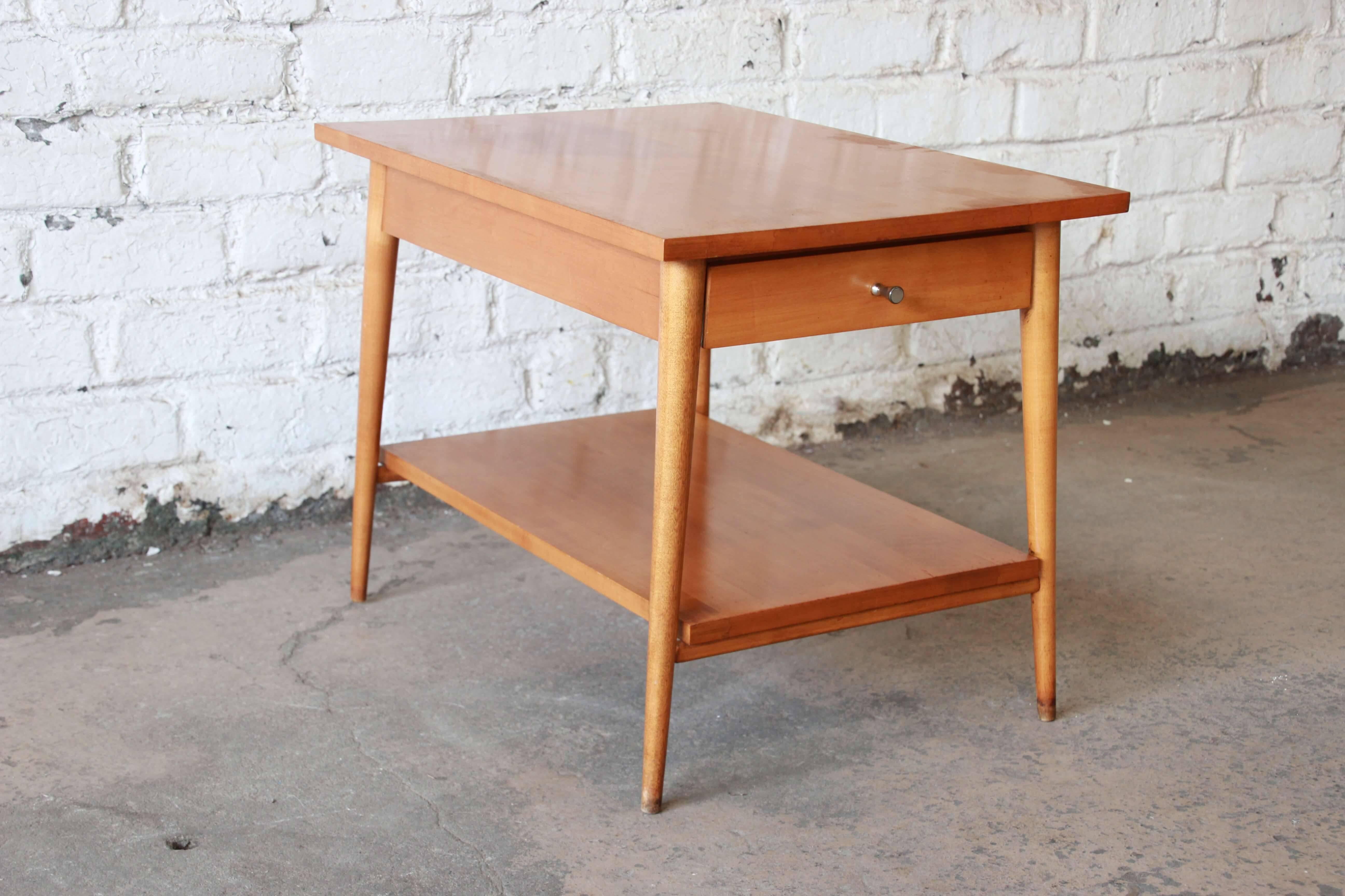 Offering a rare Mid-Century Modern two-tier side table or nightstand designed by Paul McCobb for his iconic Planner Group line for Winchendon Furniture. The table features sleek Mid-Century lines and solid birch construction. It offers one drawer