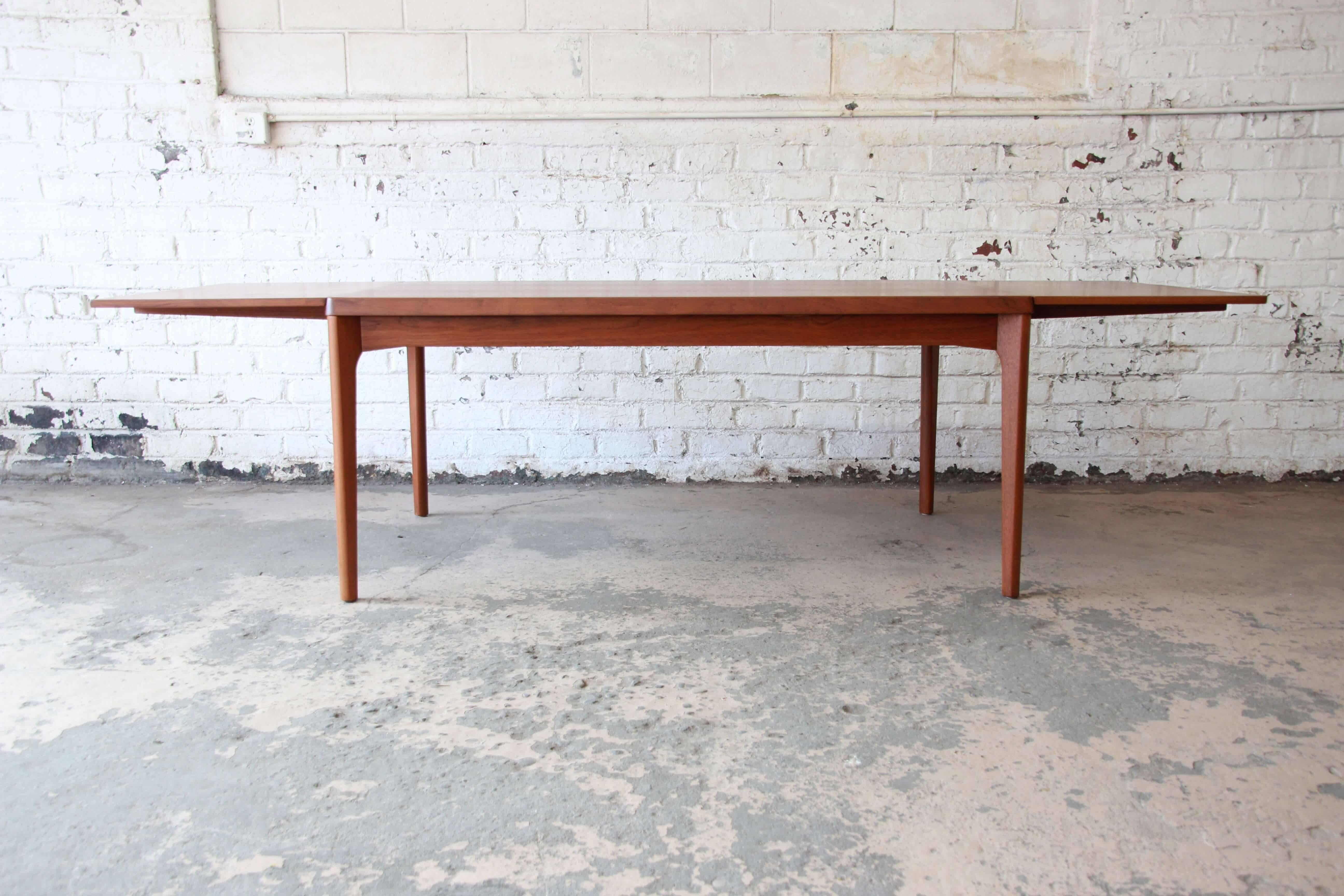 Offering an exceptional Danish Modern teak extension dining table designed by Henning Kjaernulf for Vejle Stole Mobelfabrik. The table features gorgeous teak wood grain and clean Mid-Century lines. There are stored leaves on each side of the table